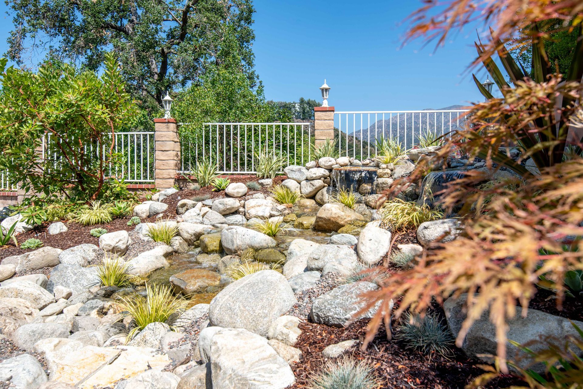 Waterfall feature with a rock garden and a decorative fence.