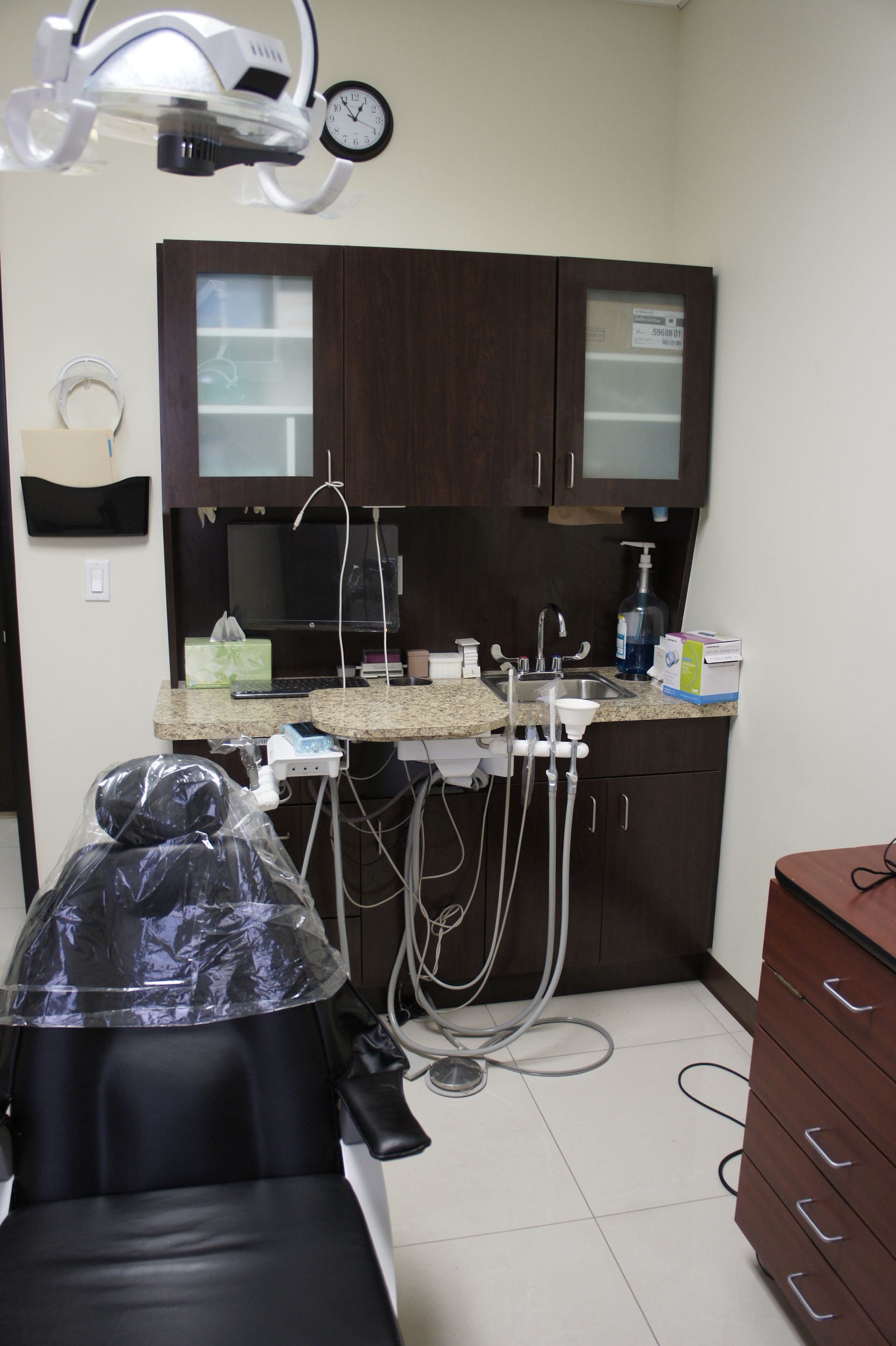 Dental office with chair, dark cabinets, and dental tools.