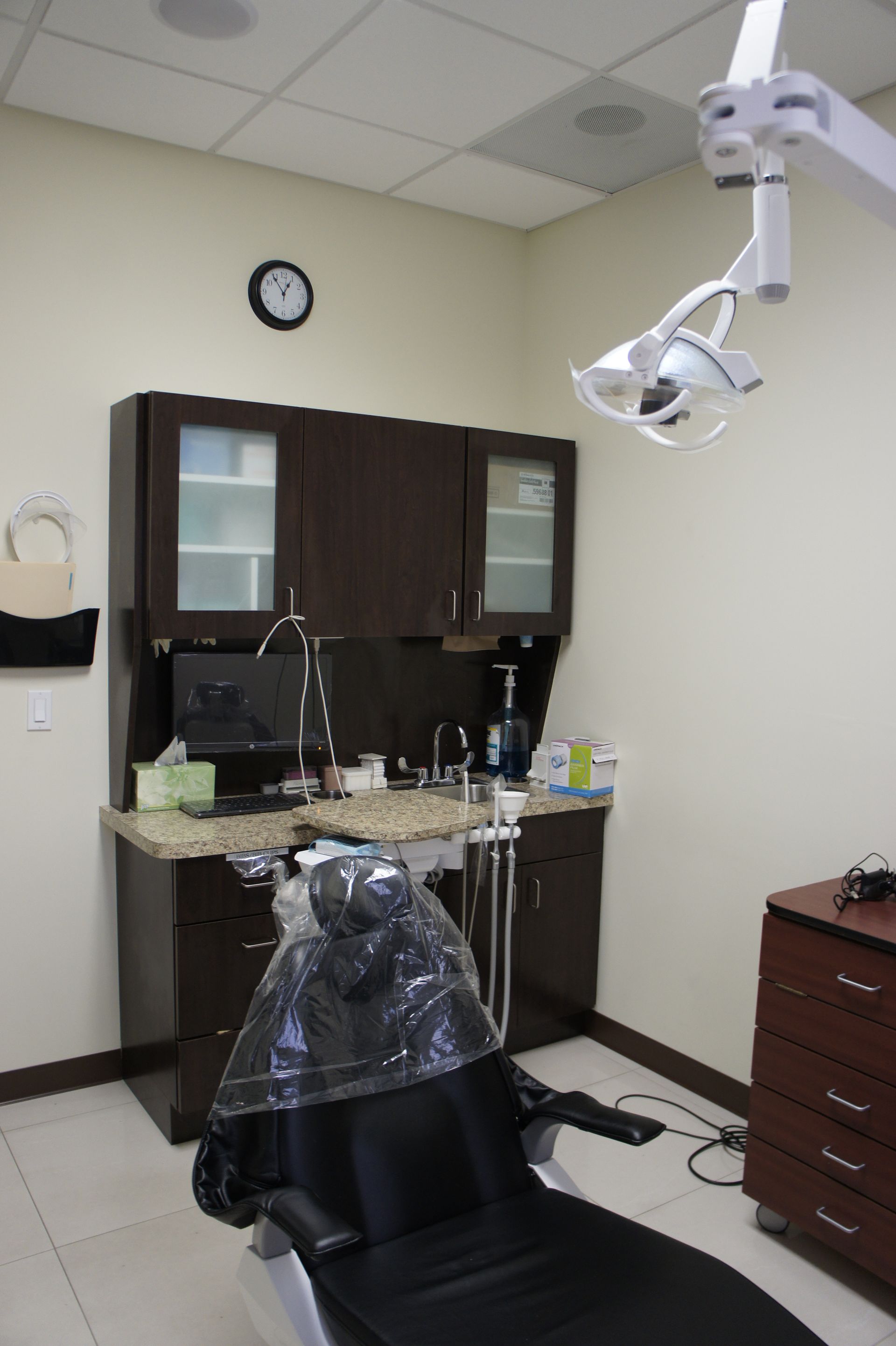 A dental office examination room with chair, cabinets, and a light.