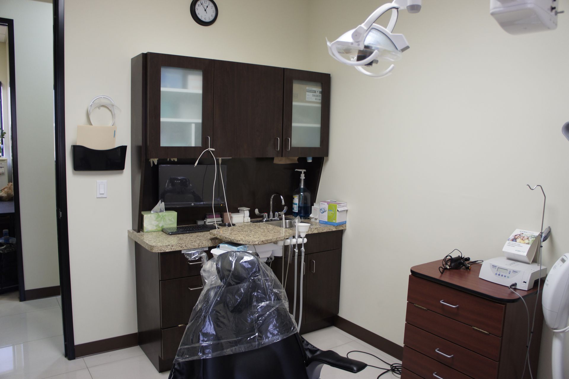 Dental exam room with dark brown cabinets, dental chair, and equipment.