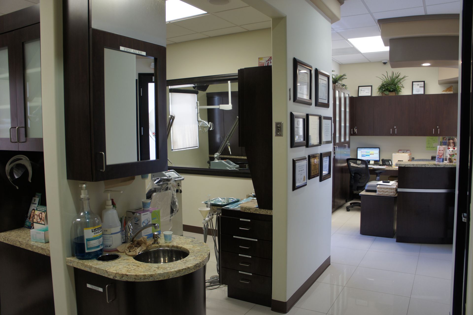 Dental office interior with cabinetry, a sink, medical equipment, and framed certifications.