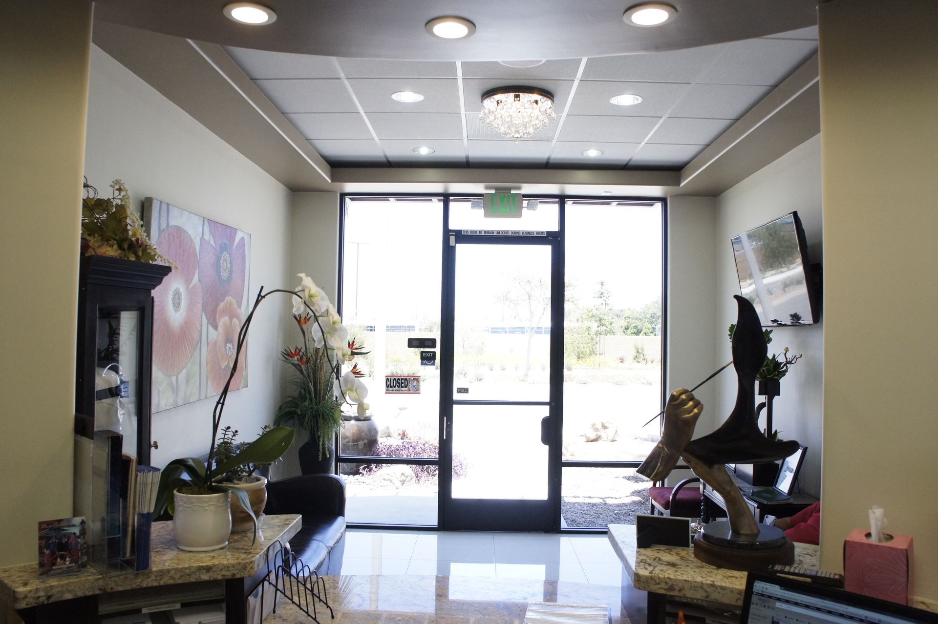 Reception area with front door, artwork, plants, and counter.