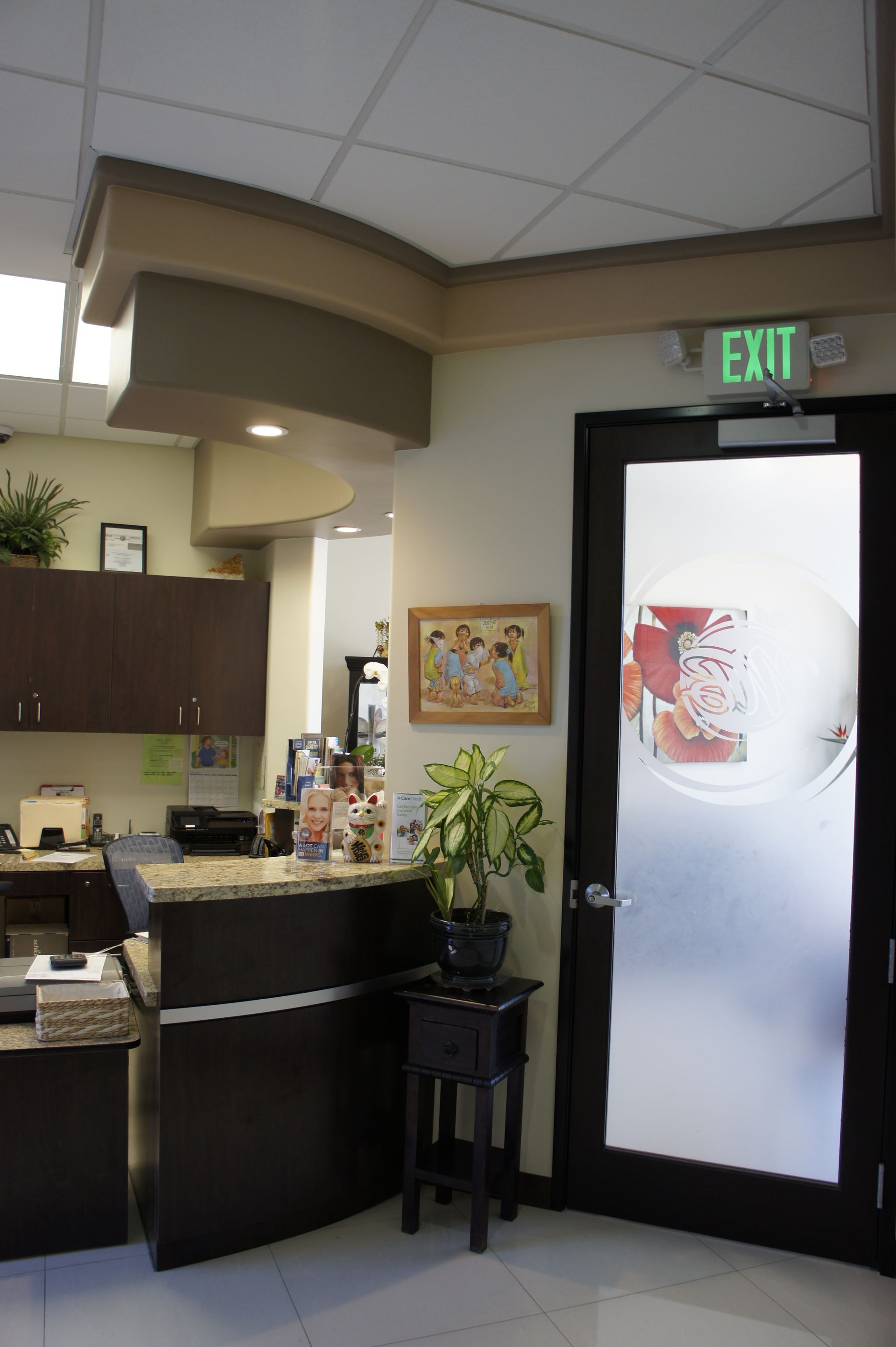 Reception area with dark counter, exit door, and small plant.