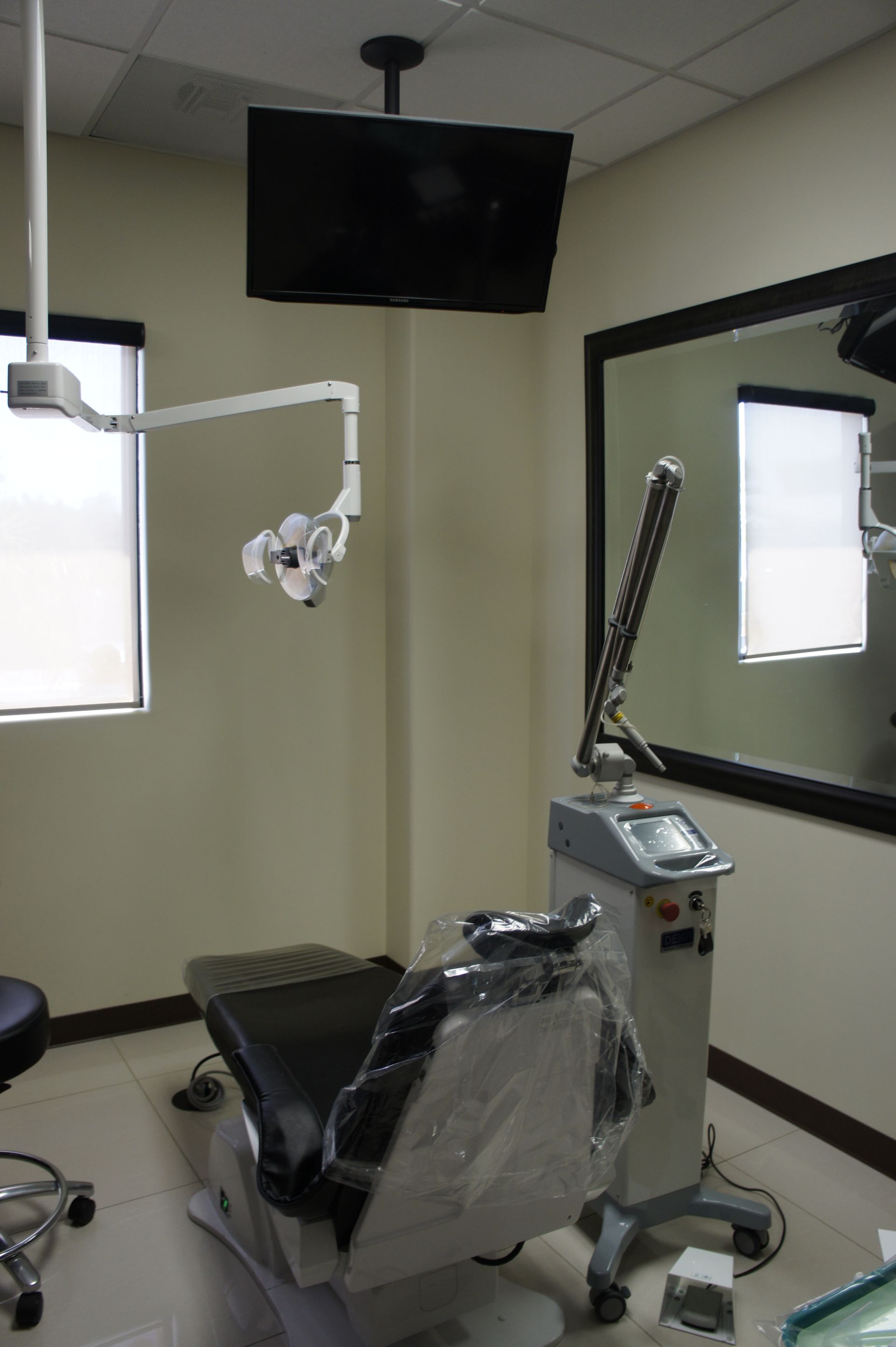 Dental operatory with chair, medical equipment, and mounted TV.