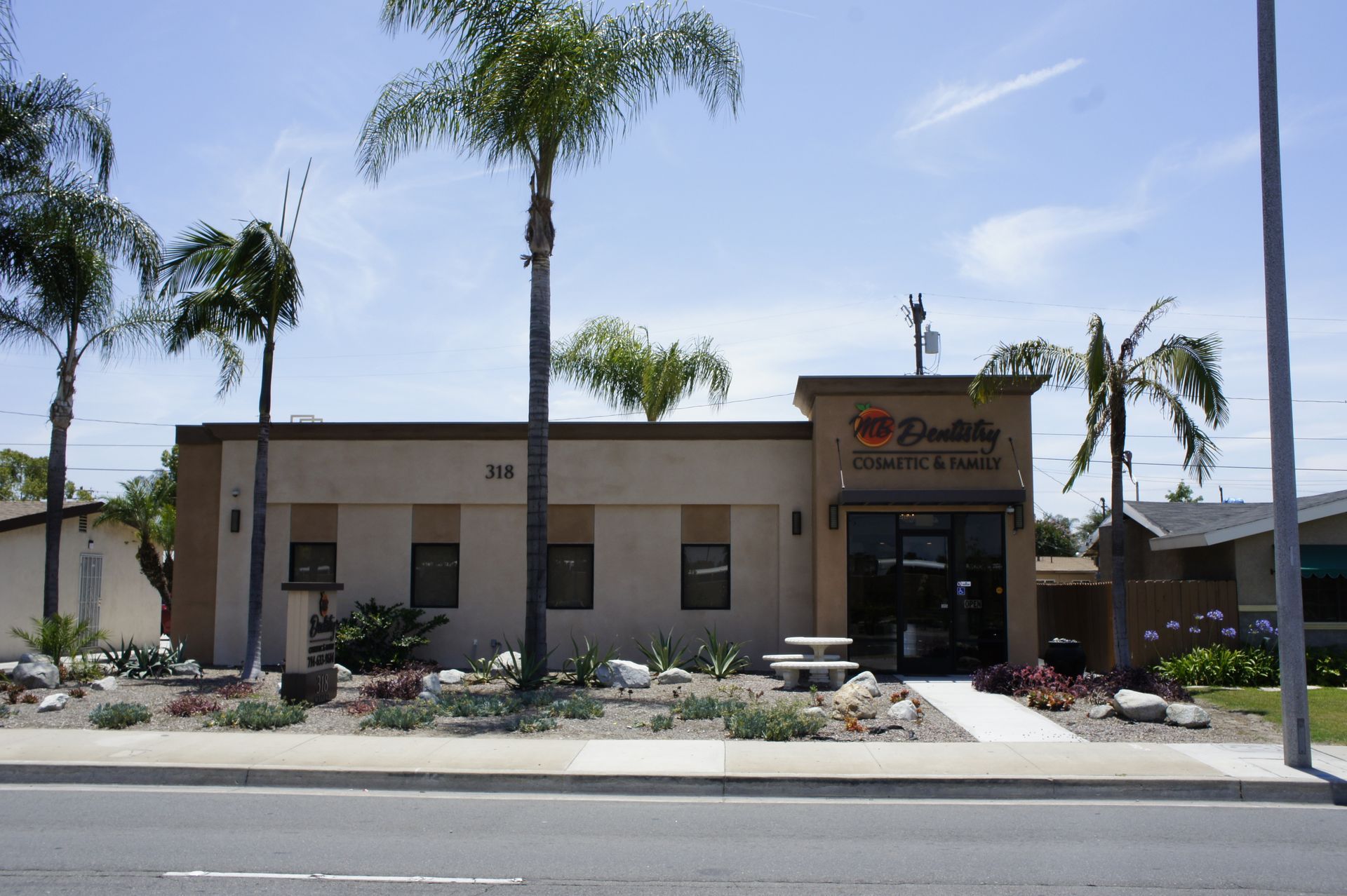 Exterior of a commercial building with palm trees and a sign that reads 
