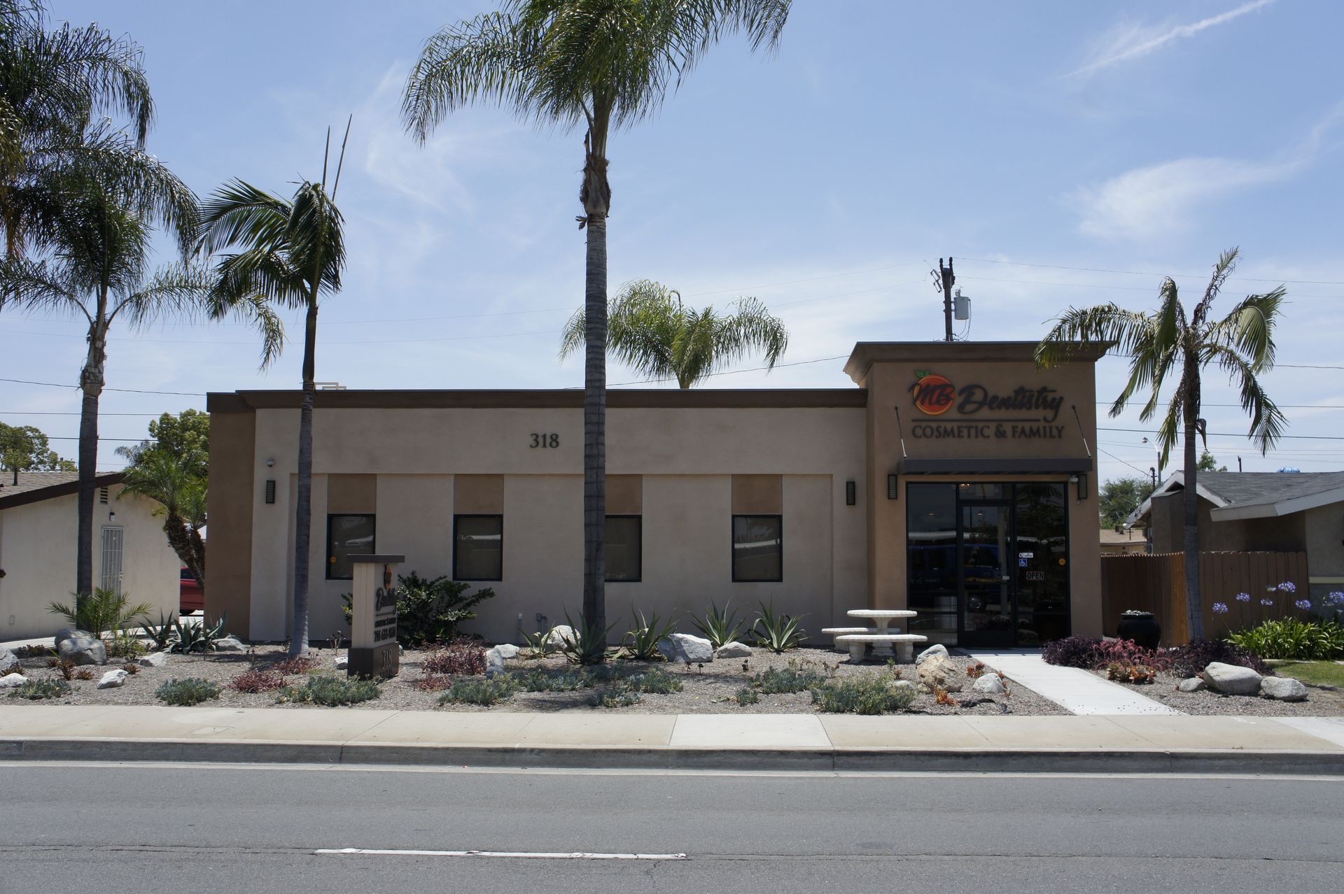 A tan commercial building with palm trees. 