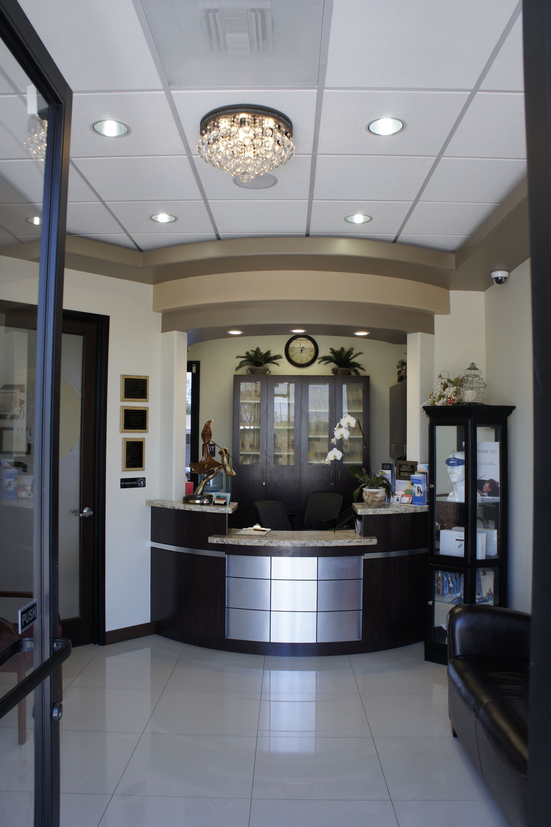 Reception area with a dark wood desk, crystal chandelier, and waiting area.