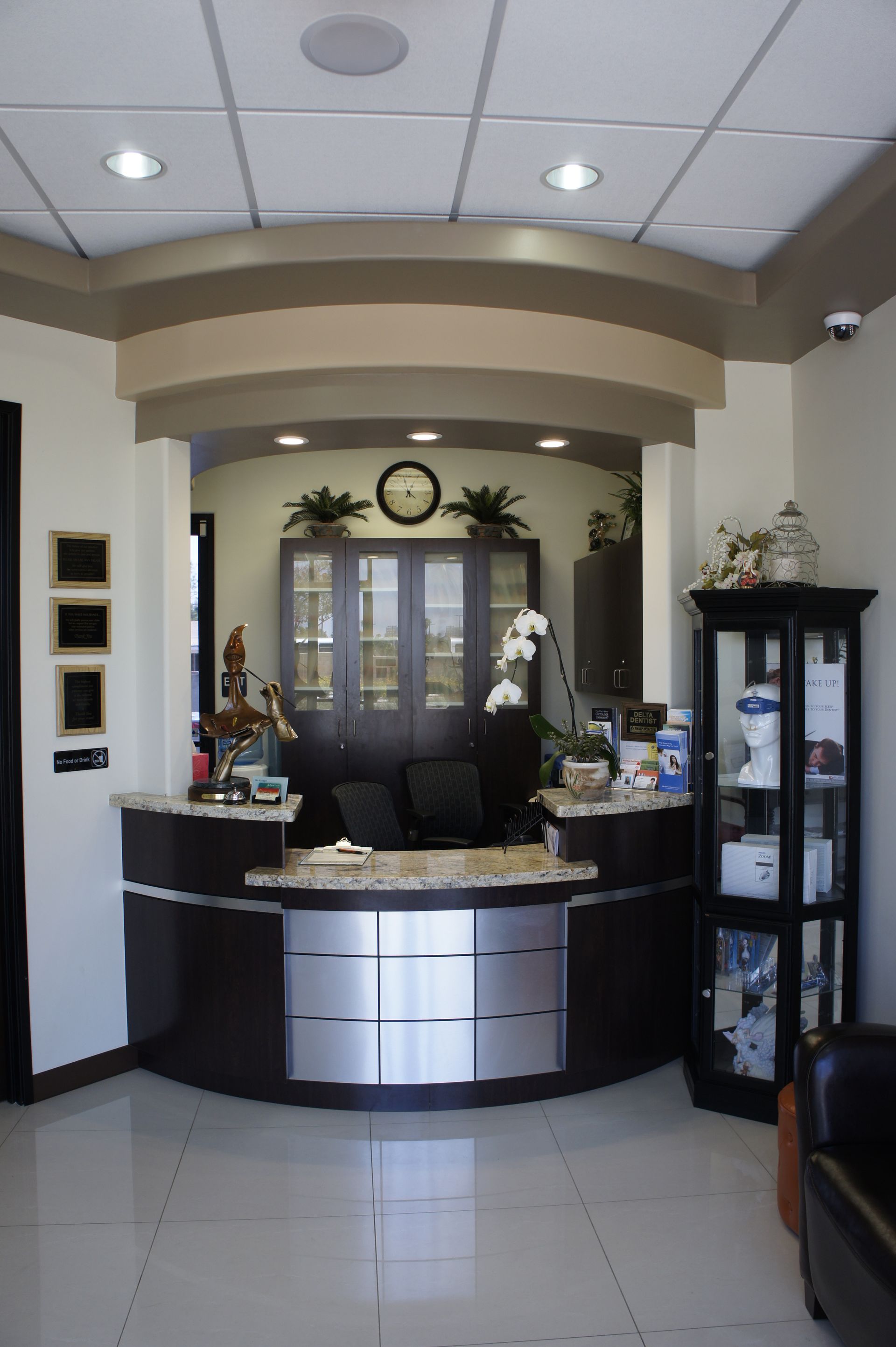 Reception desk with brown cabinetry and granite countertop, in dental office.