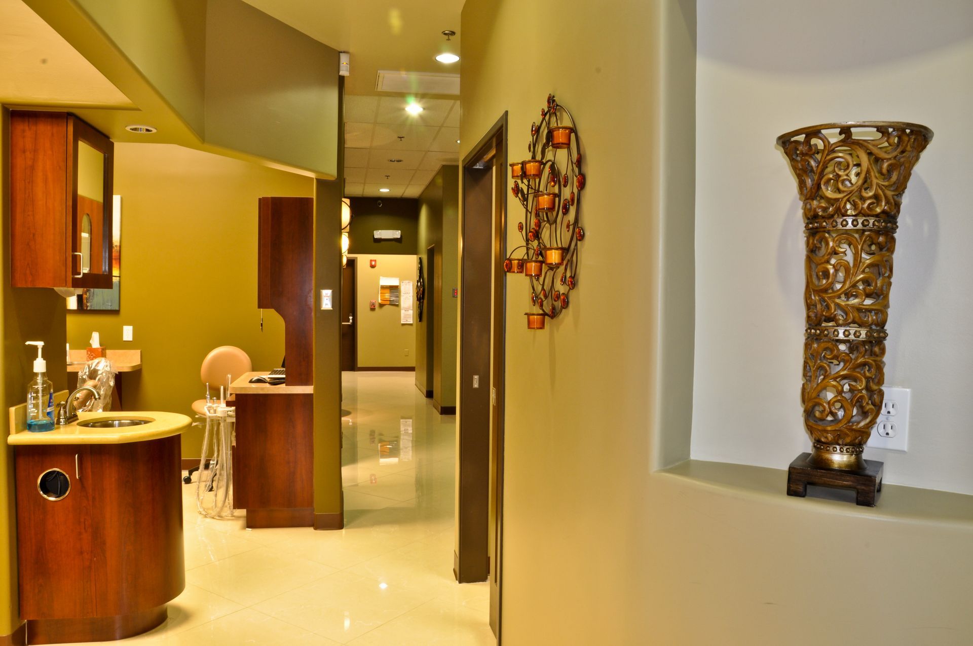 Hallway in a dental office with a decorative vase, wall sconce, and patient rooms.