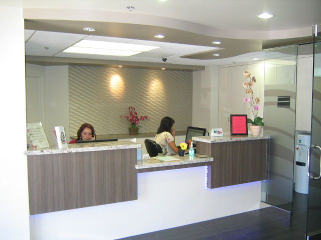 Two women work at a modern reception desk with floral arrangements.
