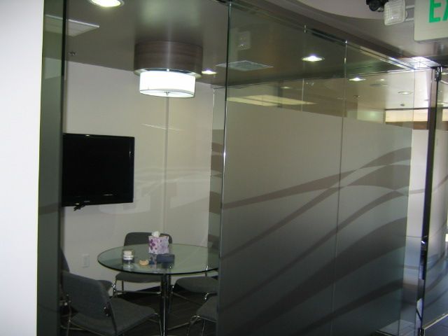 Conference room with glass walls, table, chairs, TV, and frosted design on the glass.