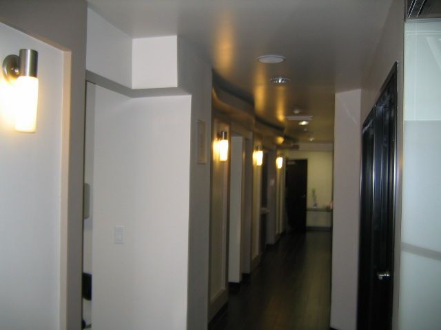 Hallway with white walls, dark floor, and recessed lighting, with doors along the sides.