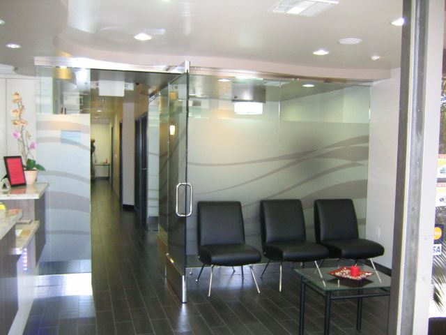 Entrance to a modern medical office with glass doors, black chairs, and a waiting area.