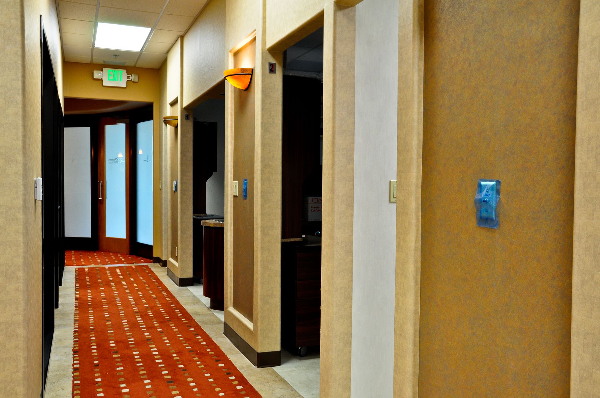 Hallway with red patterned carpet, tan walls, and doors leading to offices.