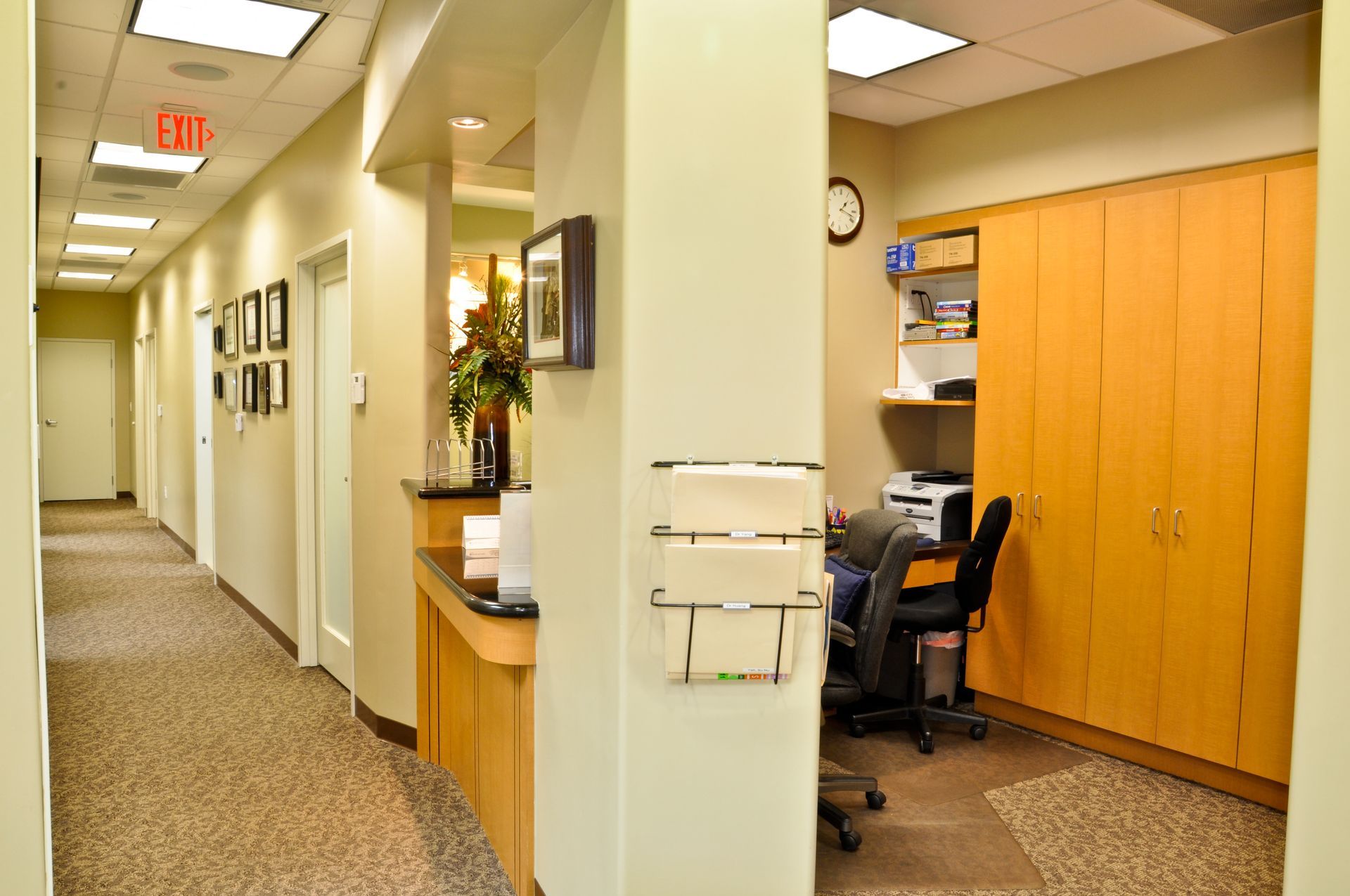 Hallway in a medical office with a reception area, cabinets, and doors.