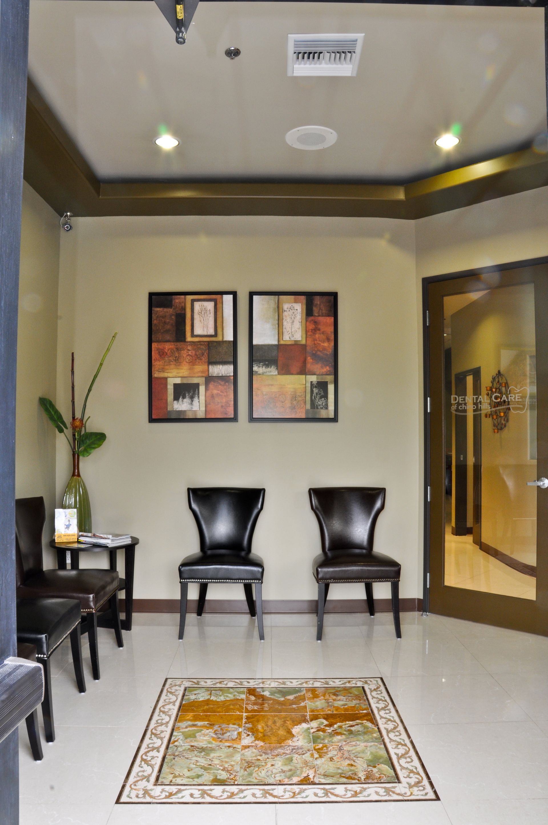 Waiting area with two black leather chairs, art, and a patterned rug. Door leads to a hallway.