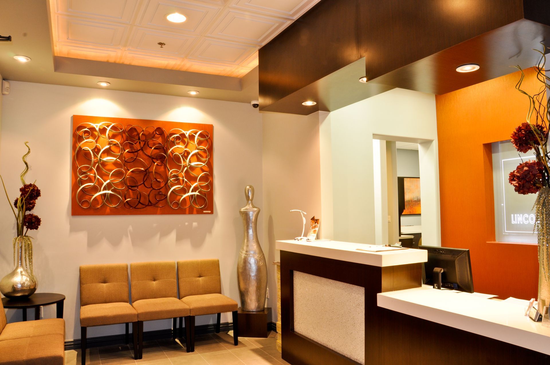 Reception area with a brown, white, and orange color scheme; waiting area with seating, art, and a reception desk.