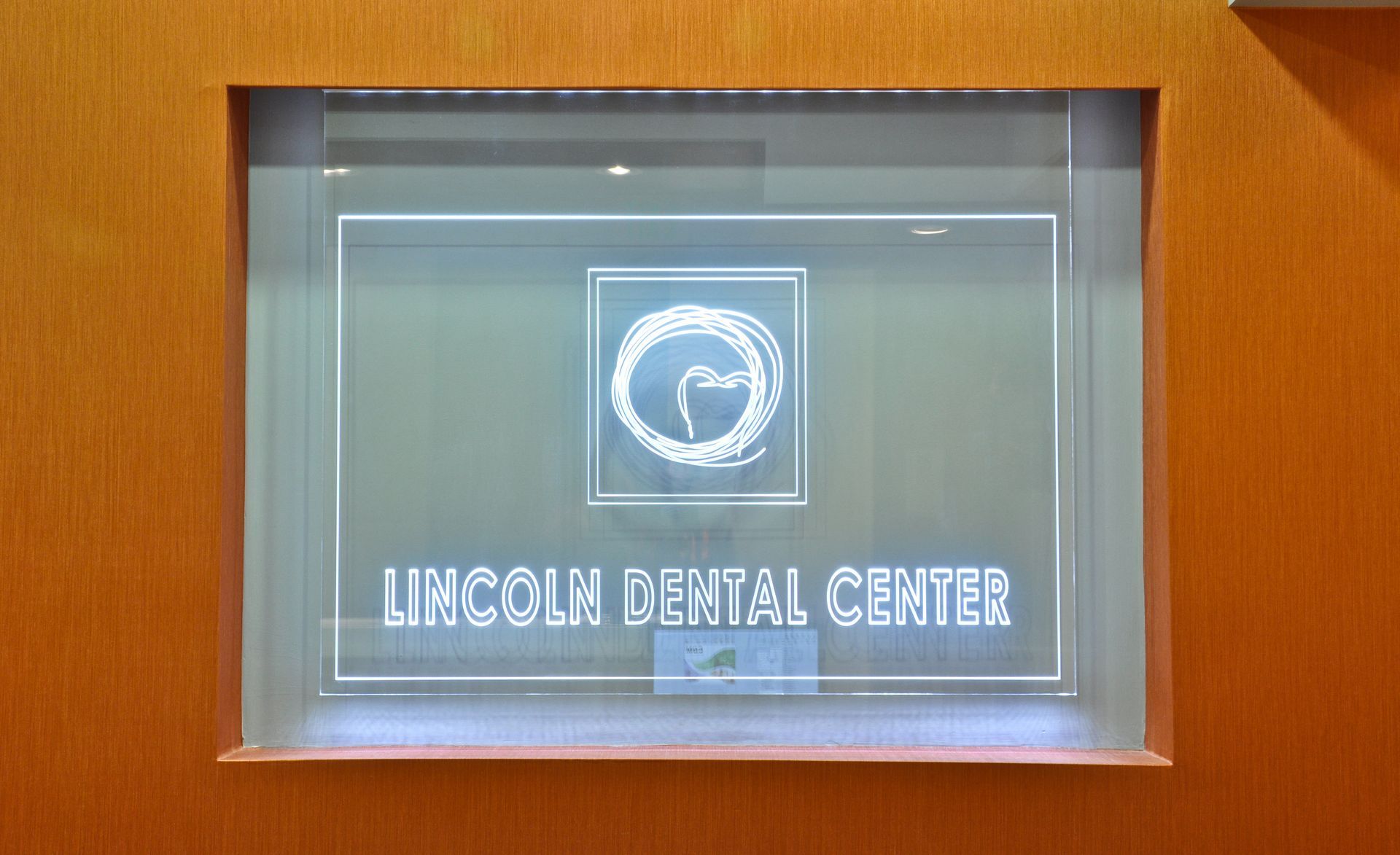 Sign for Lincoln Dental Center, white text on frosted glass within a wood-framed recess.