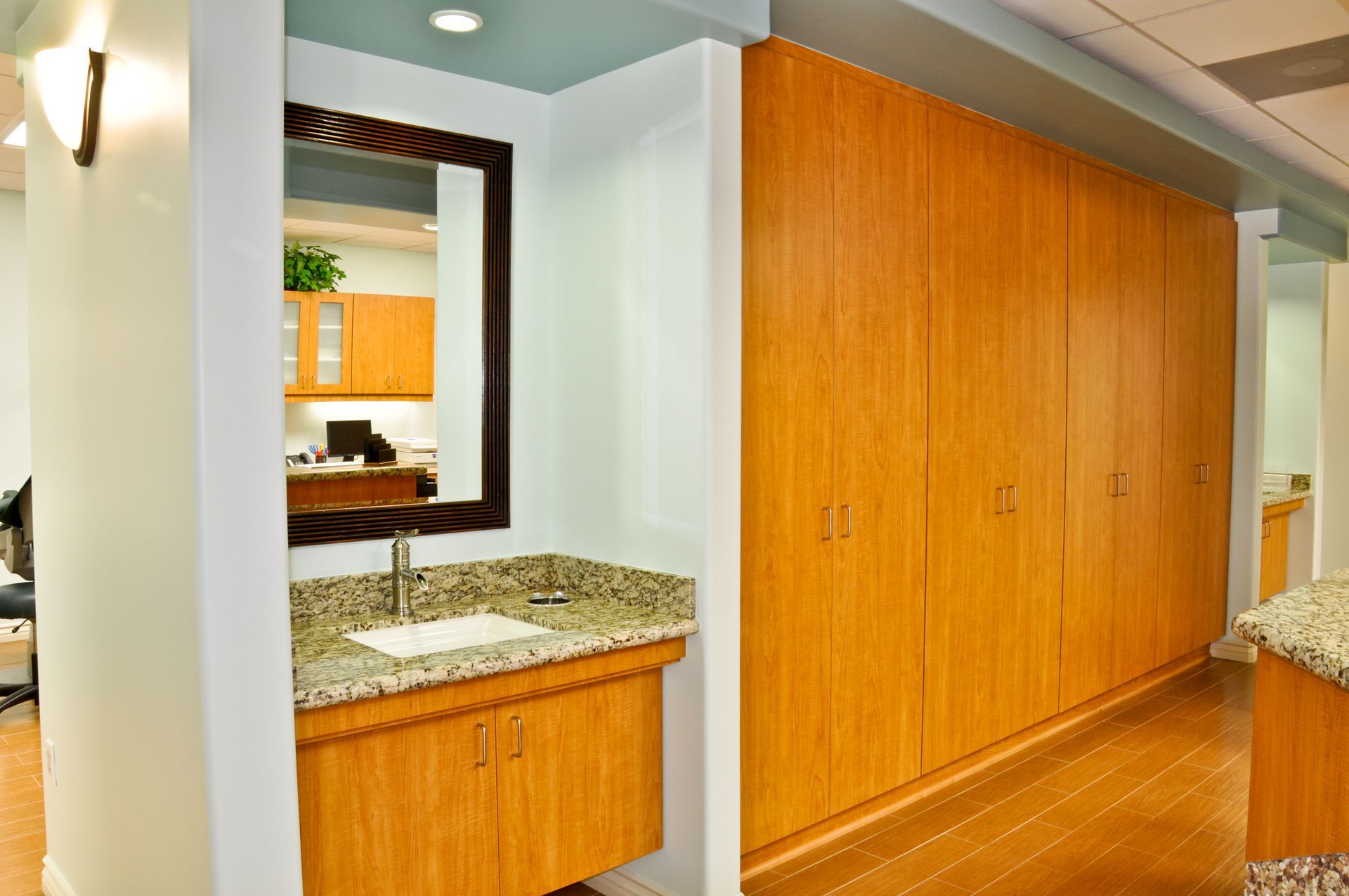 Bathroom with wood cabinets, granite countertop, and a large mirror.
