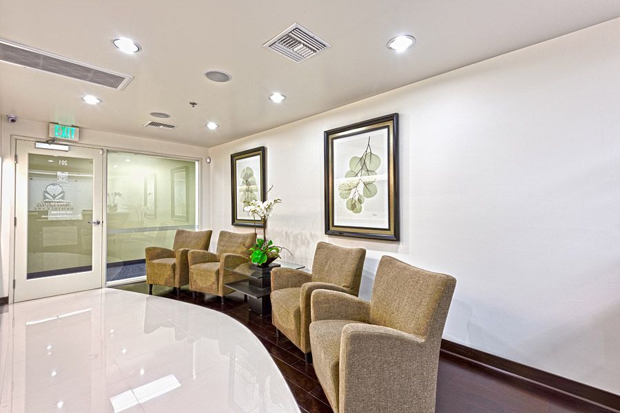 Waiting room with beige chairs, artwork, and shiny white floor.