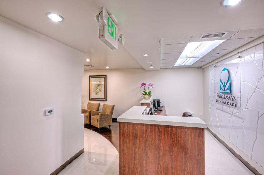Dental office waiting area with reception desk, chairs, and exit sign.