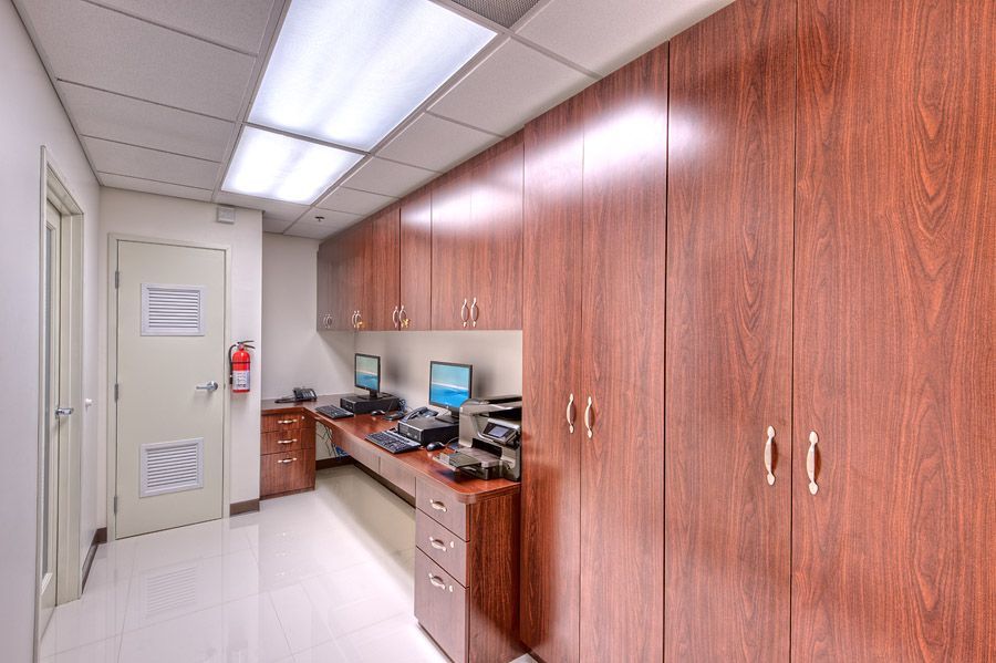 Hallway with wood cabinets and desks, computers, and a door.