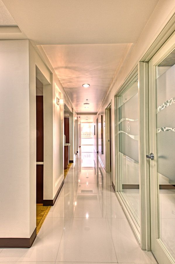 Long, bright hallway with white walls, glossy floor, and doors on either side.