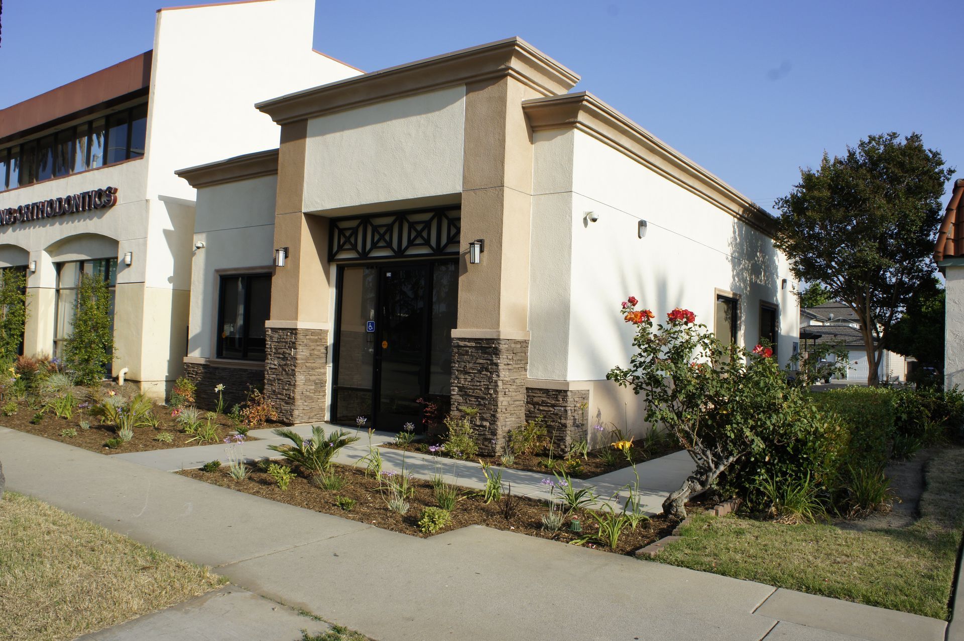 Storefront with tan stucco walls, stone accents, and a small garden.