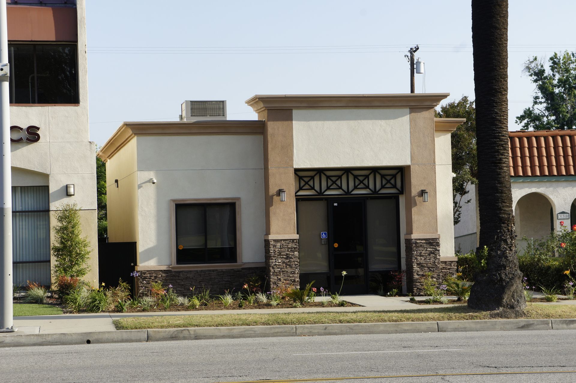 Small tan building with stone accents and a decorated entrance, likely a commercial property.