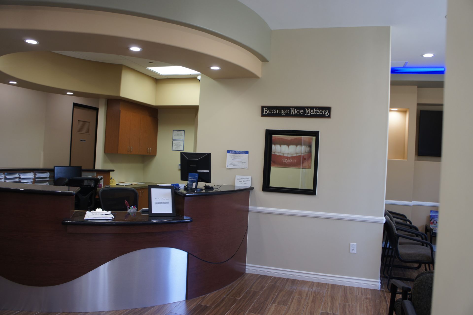 Reception area of a dental office, with a desk, artwork, and waiting chairs.