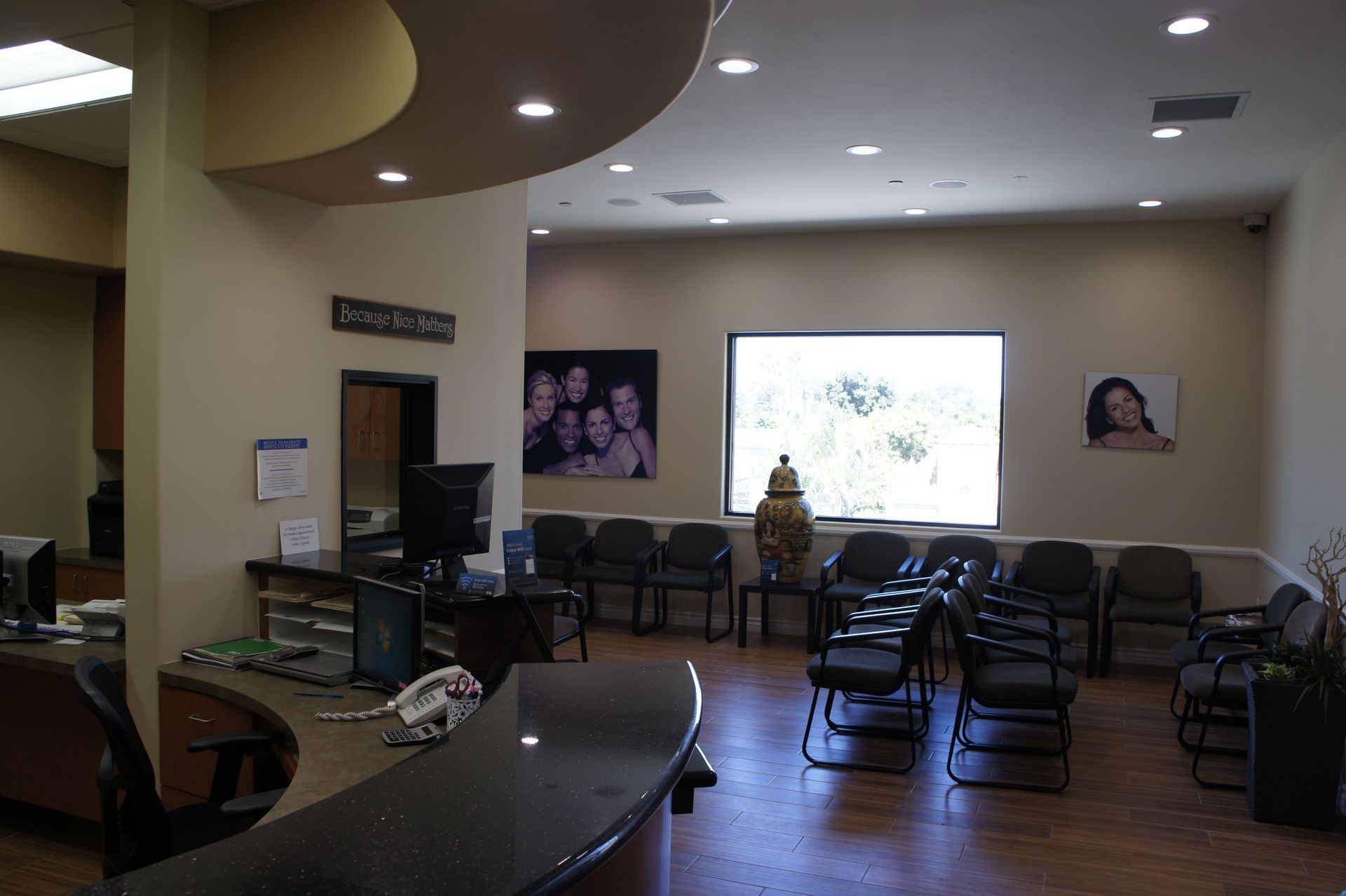 Reception area of a medical office with chairs for patients, a desk, and framed photos on the wall.
