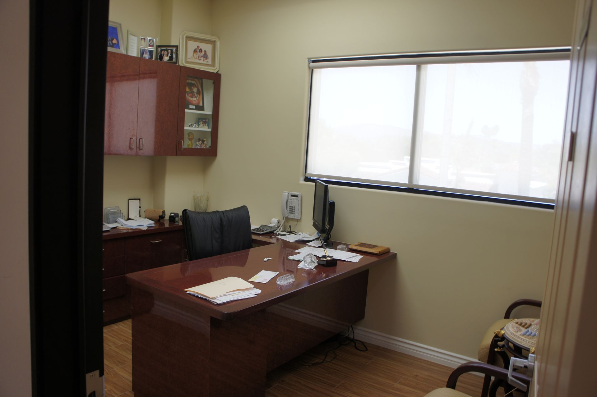 Office with desk, chair, window, cabinets, and personal items.