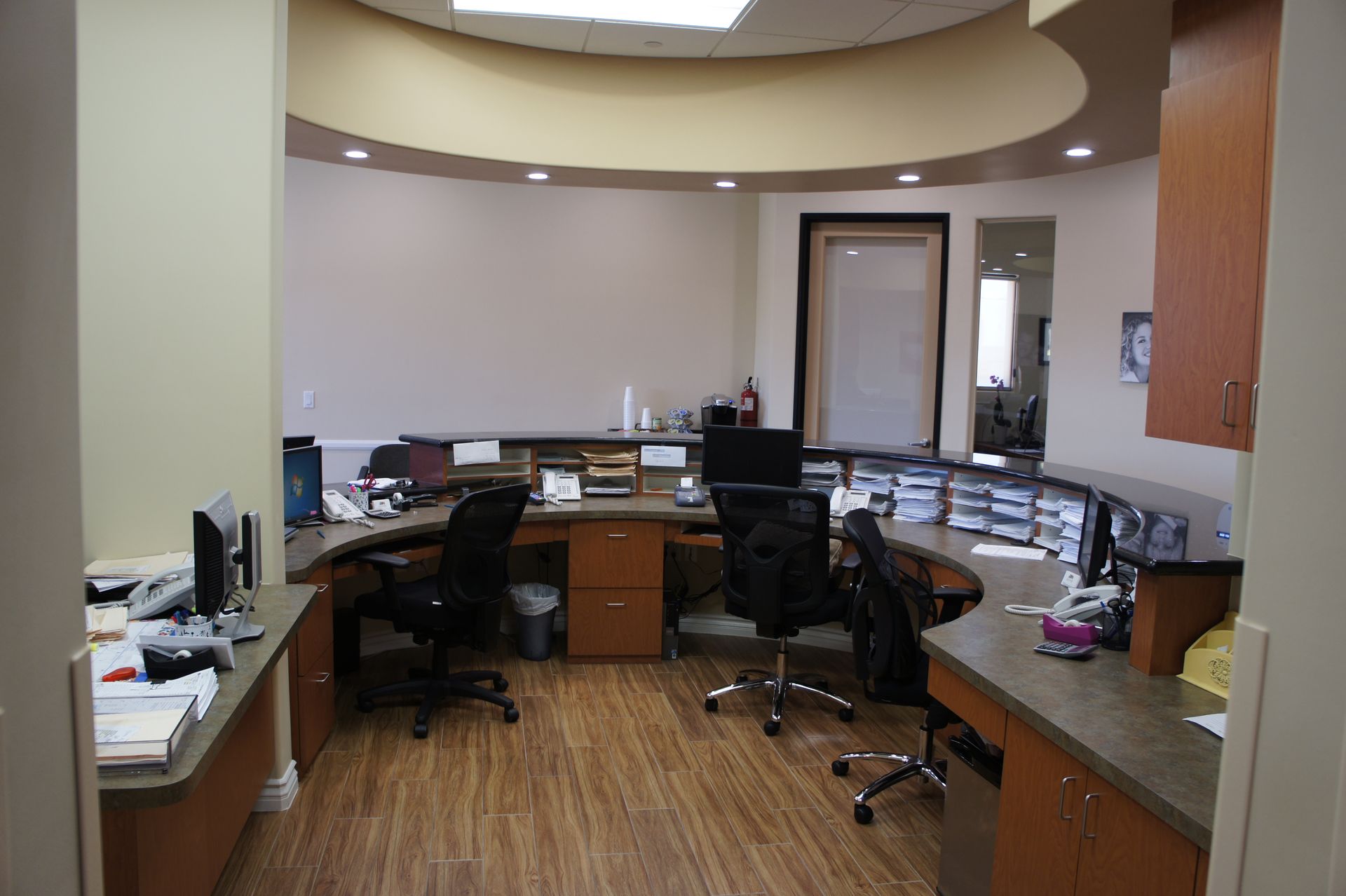 Reception area with curved counter, desks, chairs, and wood flooring.