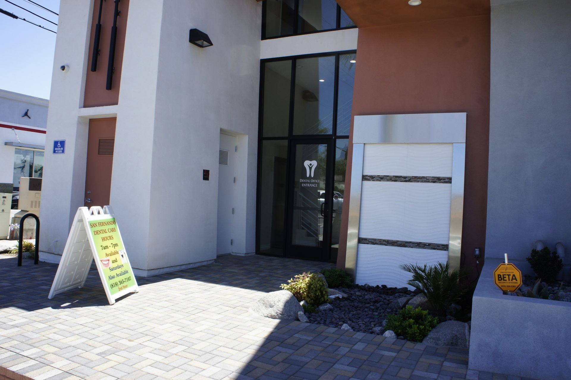Exterior of dental office with sign, glass door entrance, and modern facade.