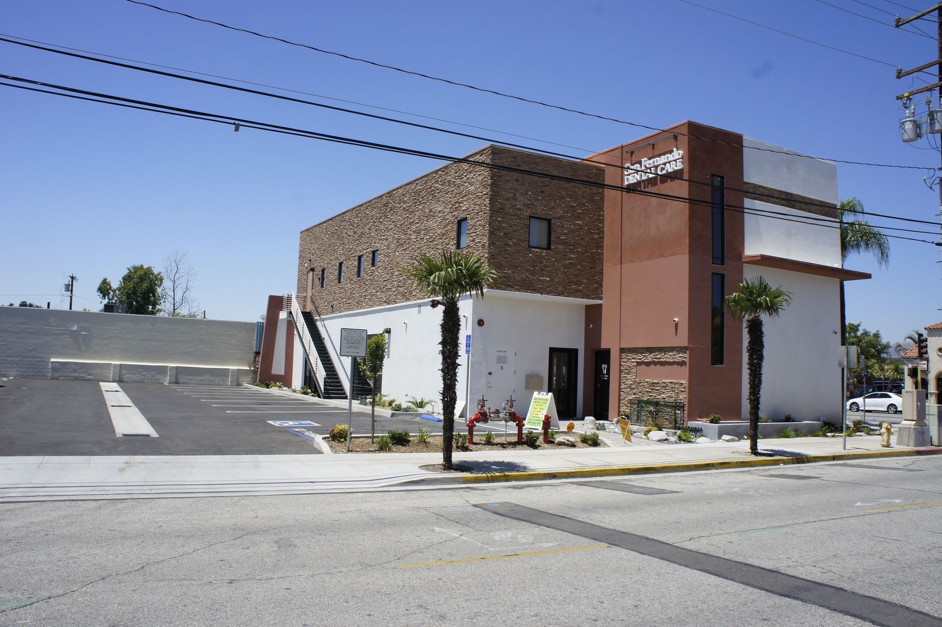 Building with brown brick and white stucco, street in front.