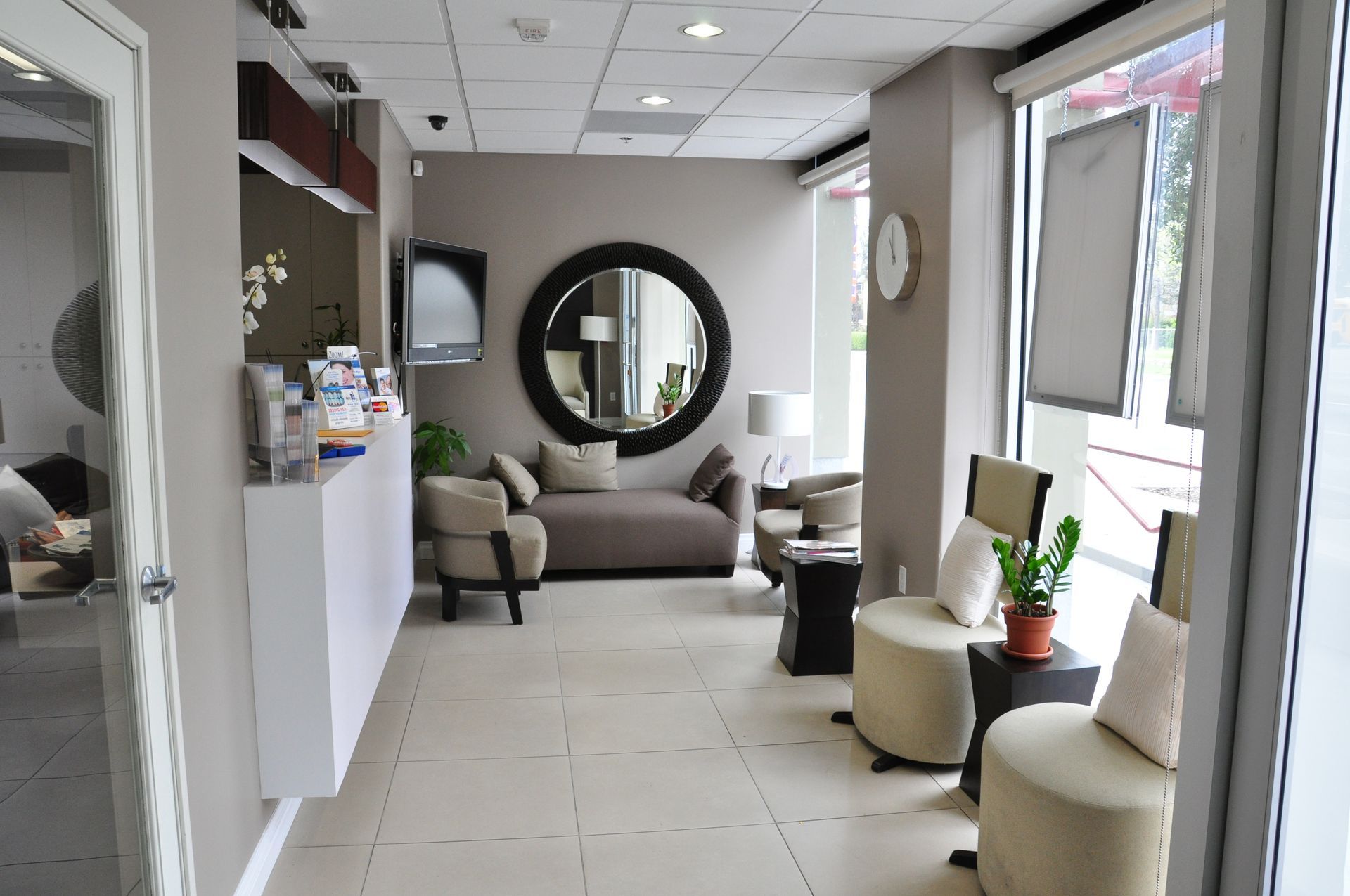 Lobby with neutral colors, seating, a round mirror, and a reception desk.