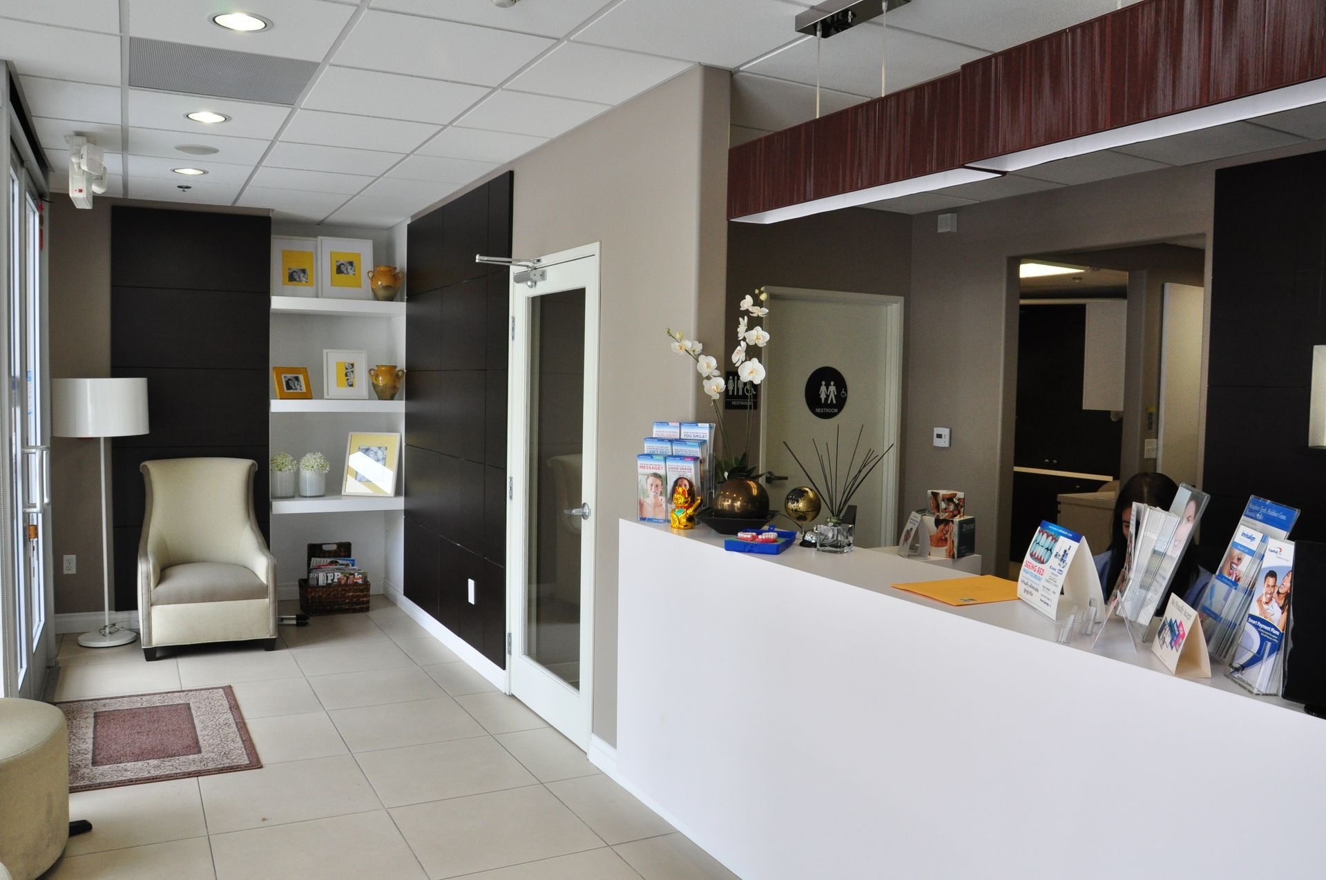 Reception area with white desk, dark accent wall, chair, and brochures.
