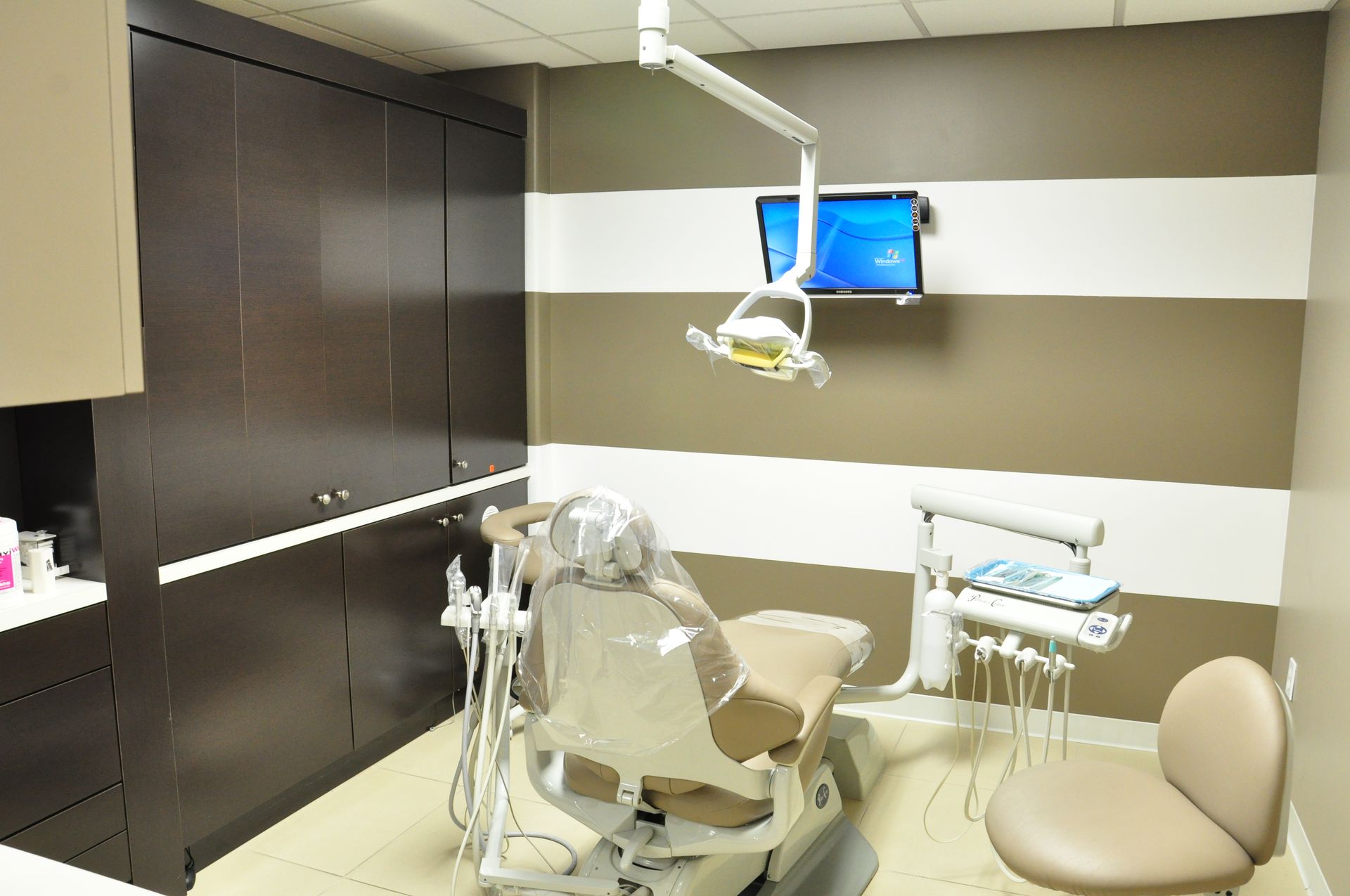 Dental exam room with a brown and white striped wall, dental chair, and equipment.