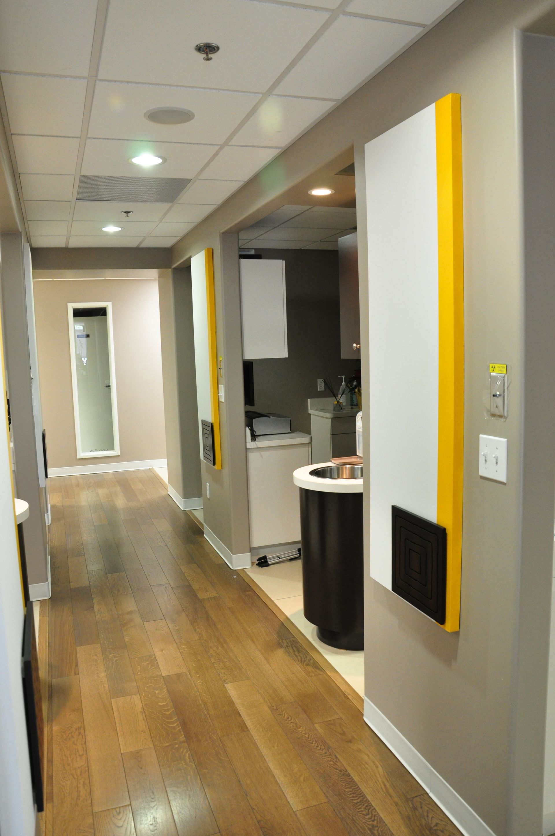 Hallway with wood floor, beige walls, white and yellow wall panels, and an open doorway.