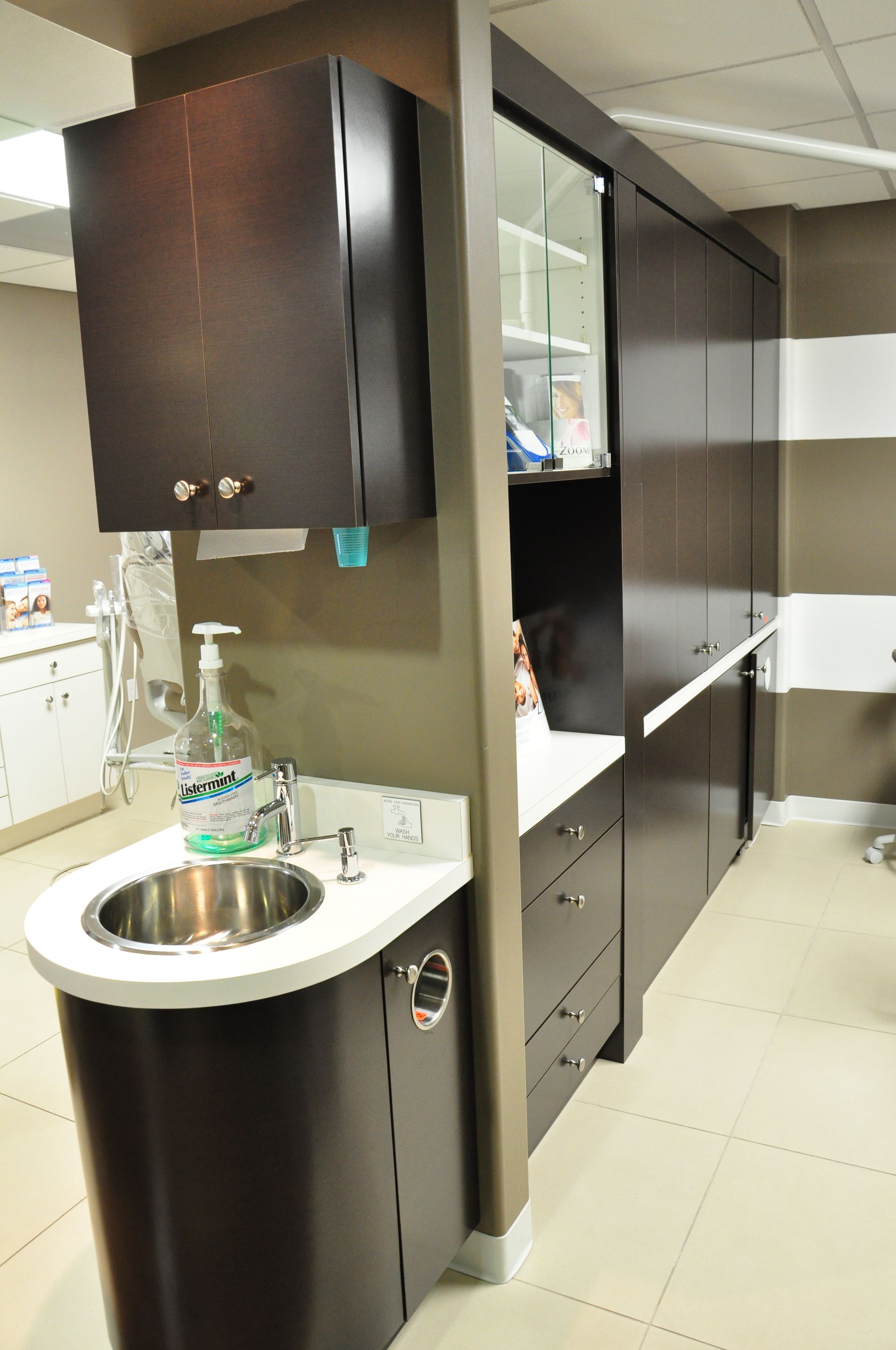 Dark wood dental cabinet with sink, counter, and upper cabinets.
