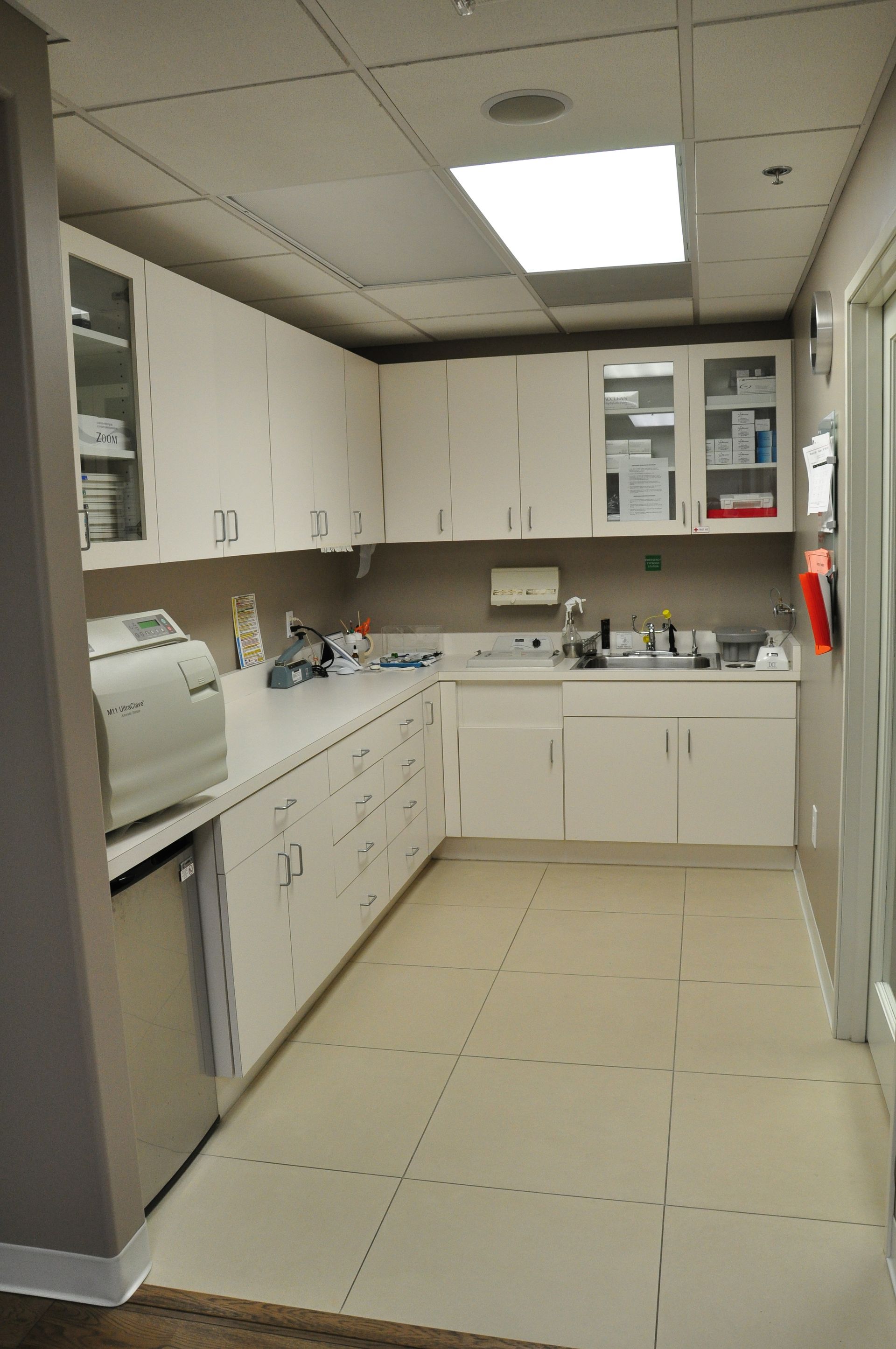 A sterile medical supply room with white cabinets, countertops, and sterilization equipment.
