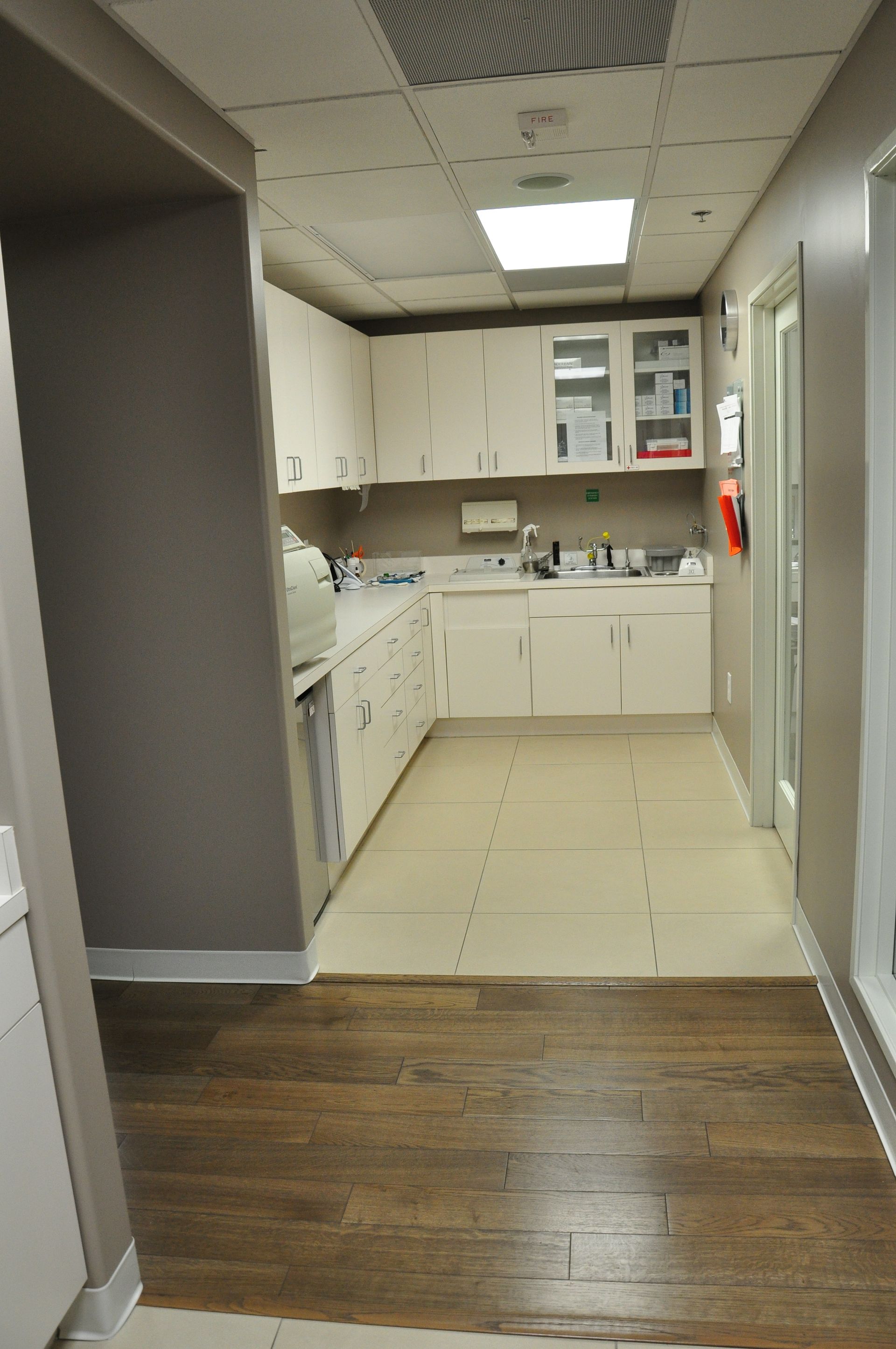 Hallway with dark wood floor, white cabinets, and a stainless steel appliance.
