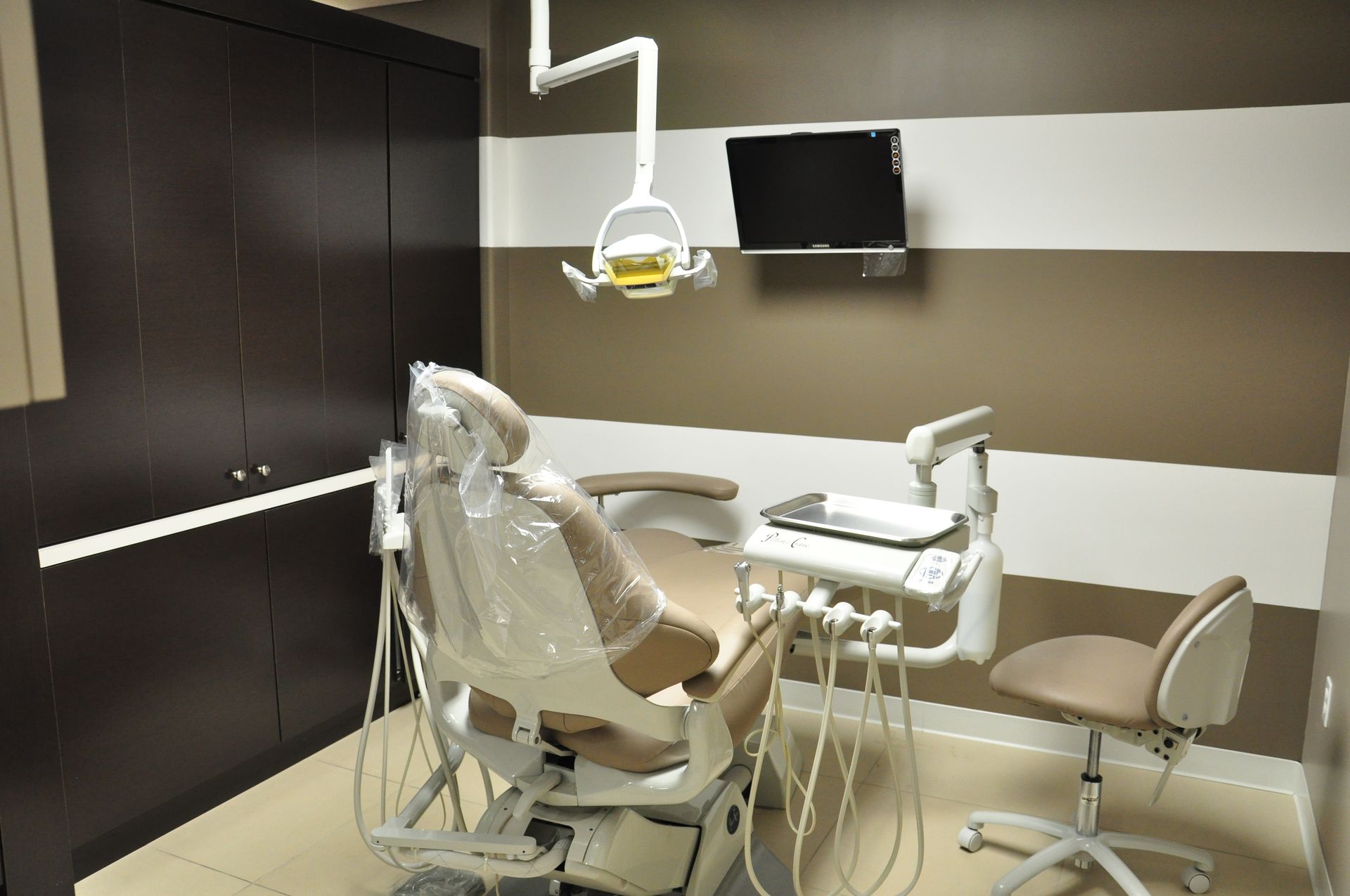 Dental chair in an examination room, beige and brown color scheme.