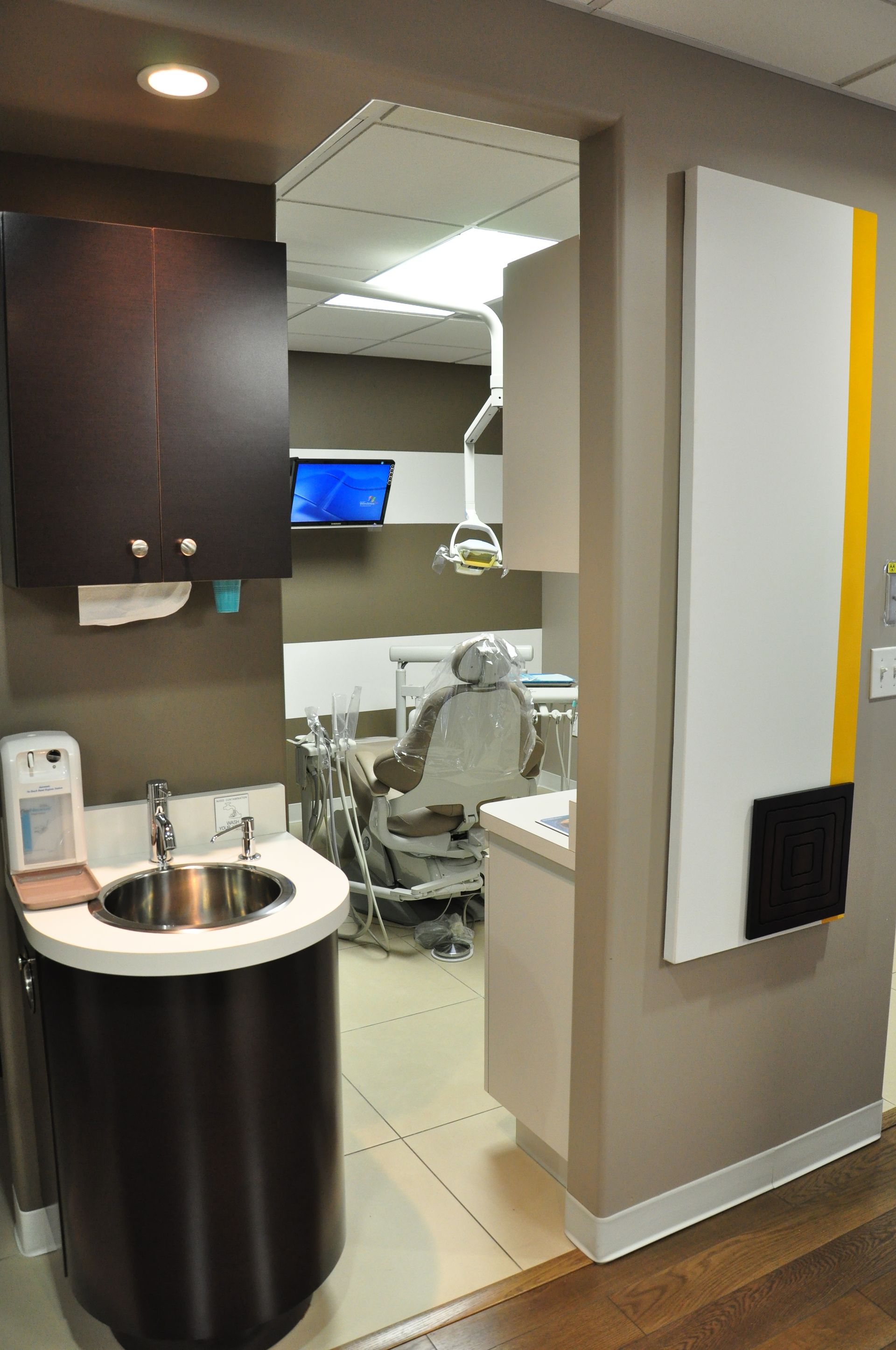 Dental office with sink, cabinets, and open doorway to exam room.