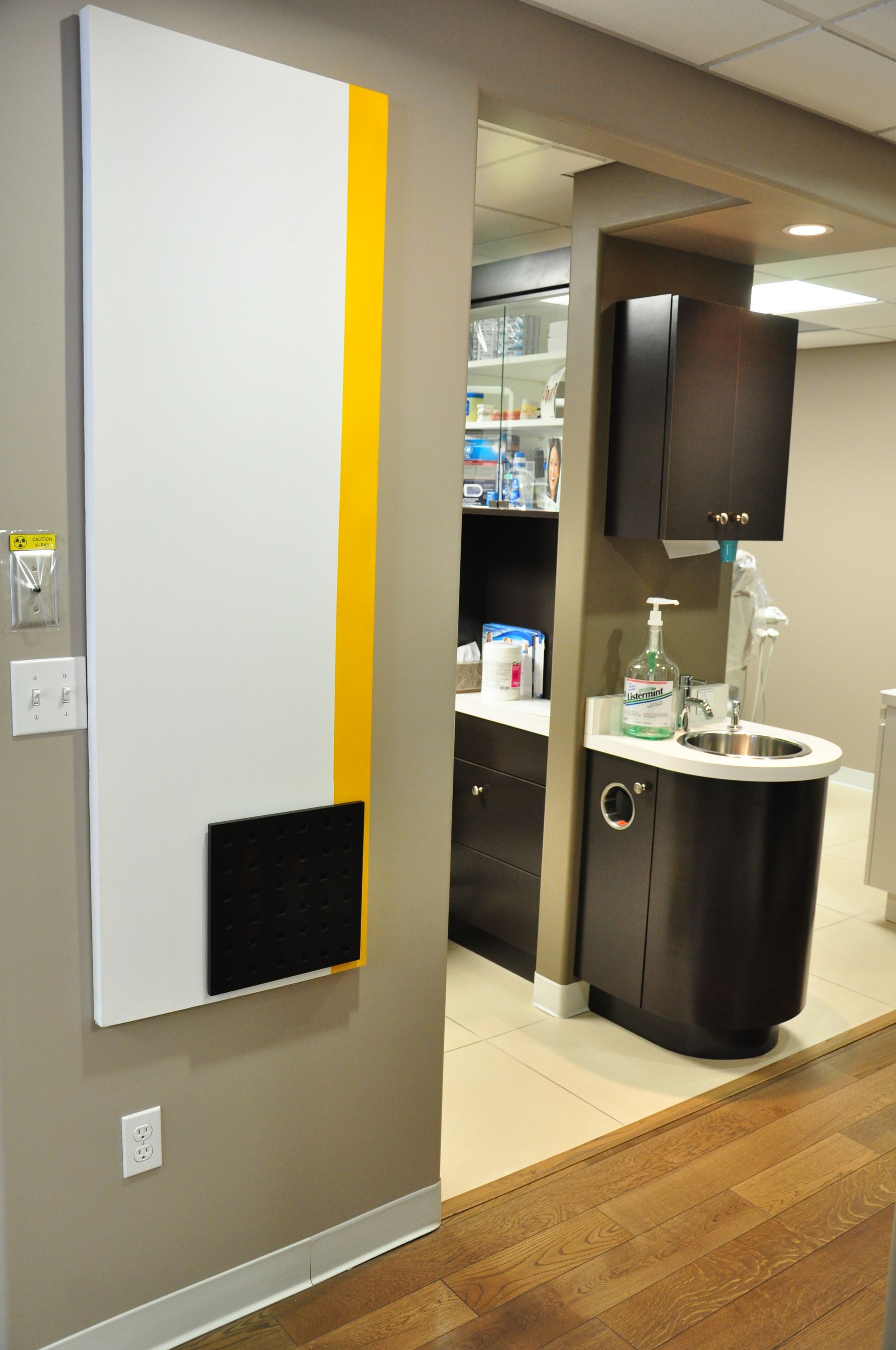 White and yellow wall art beside an open doorway into a dentist office.