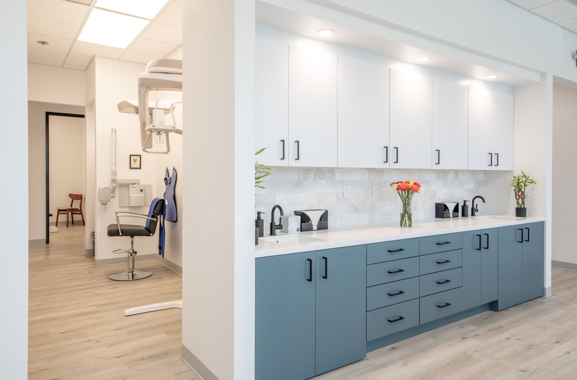 Dental office interior with blue and white cabinets, countertop with sinks, and hallway.