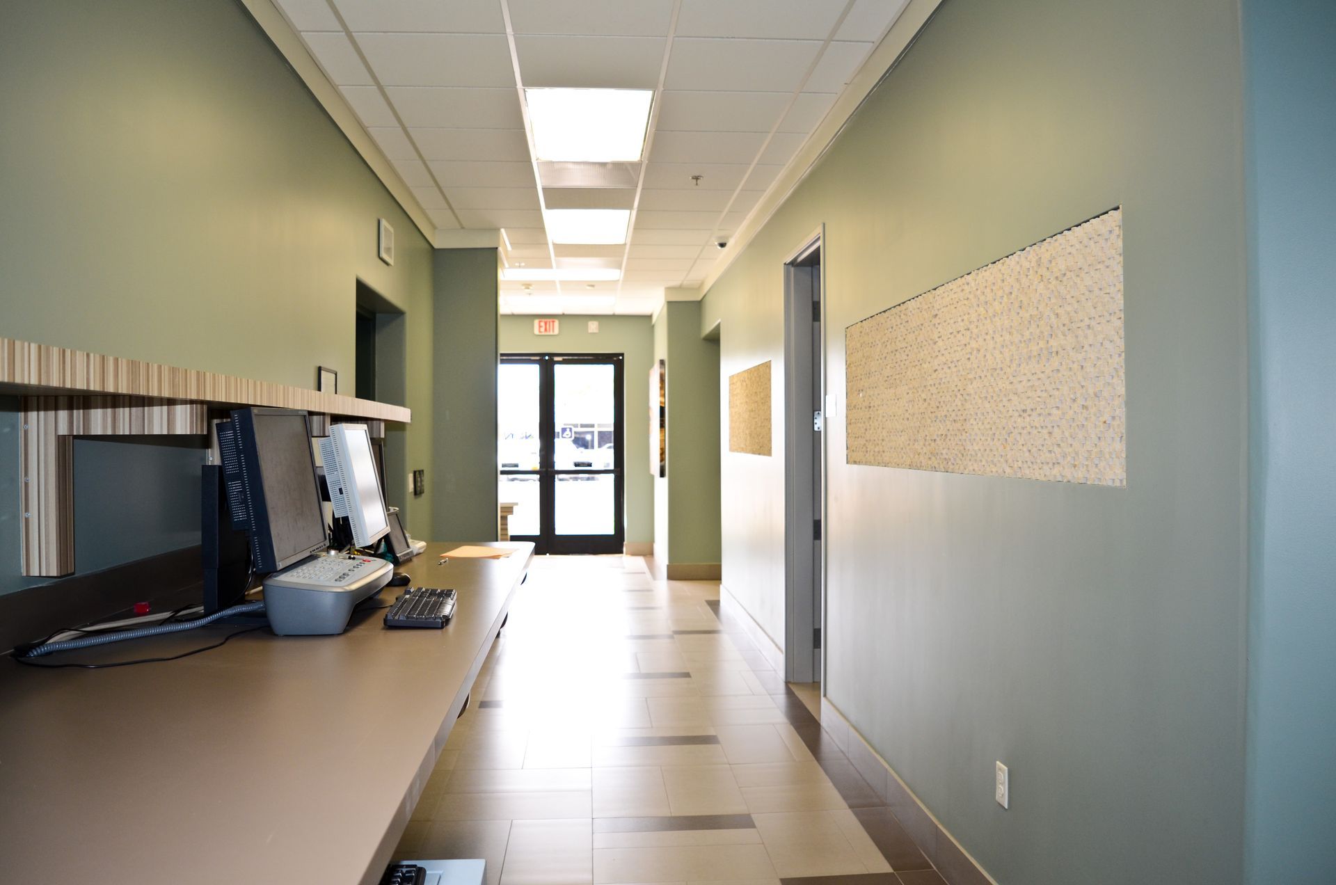 Long hallway with a desk on the left, doors on the right, and a doorway at the end.