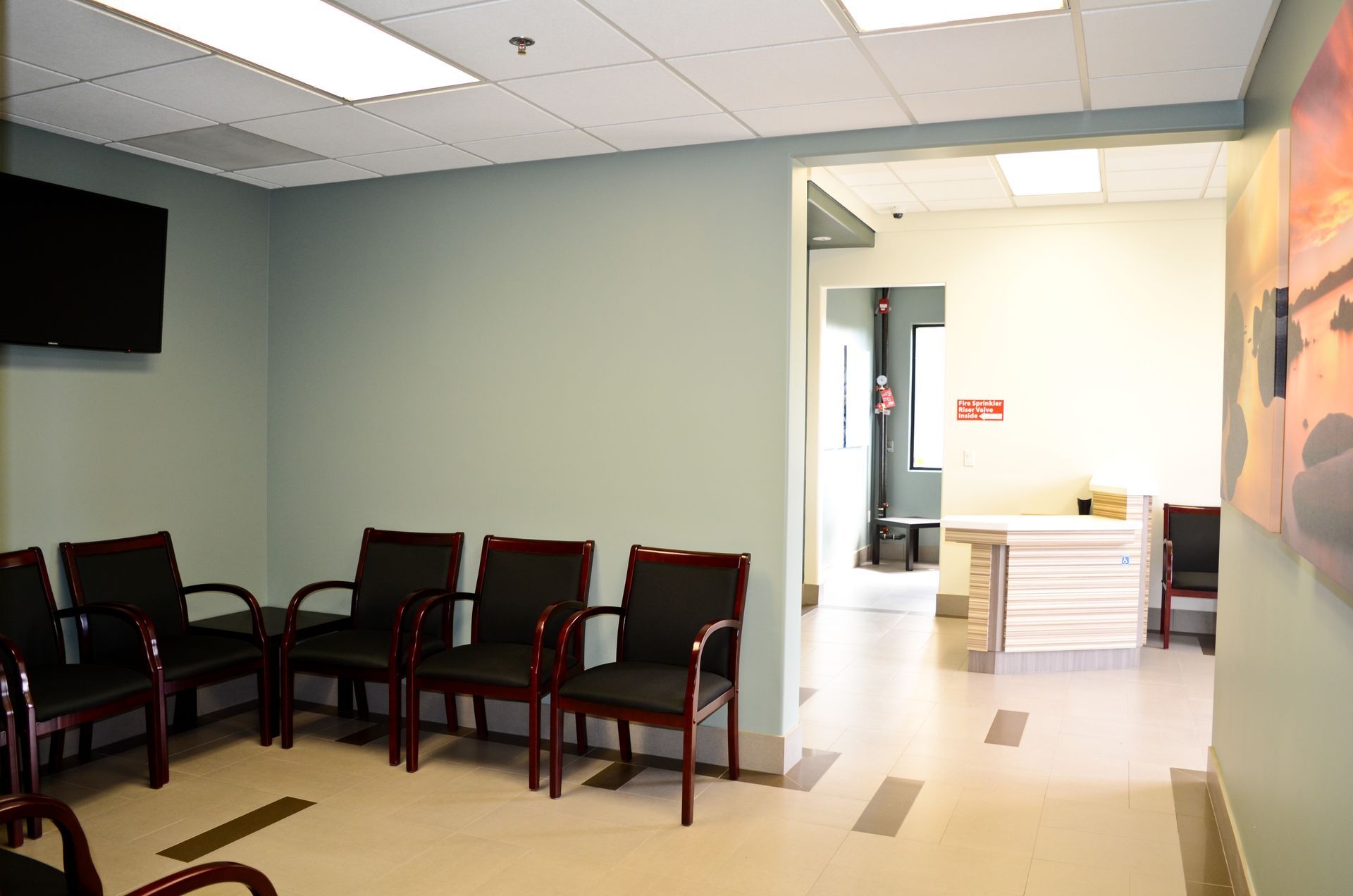 A waiting room with chairs, a TV, and an open doorway leading to a hallway.