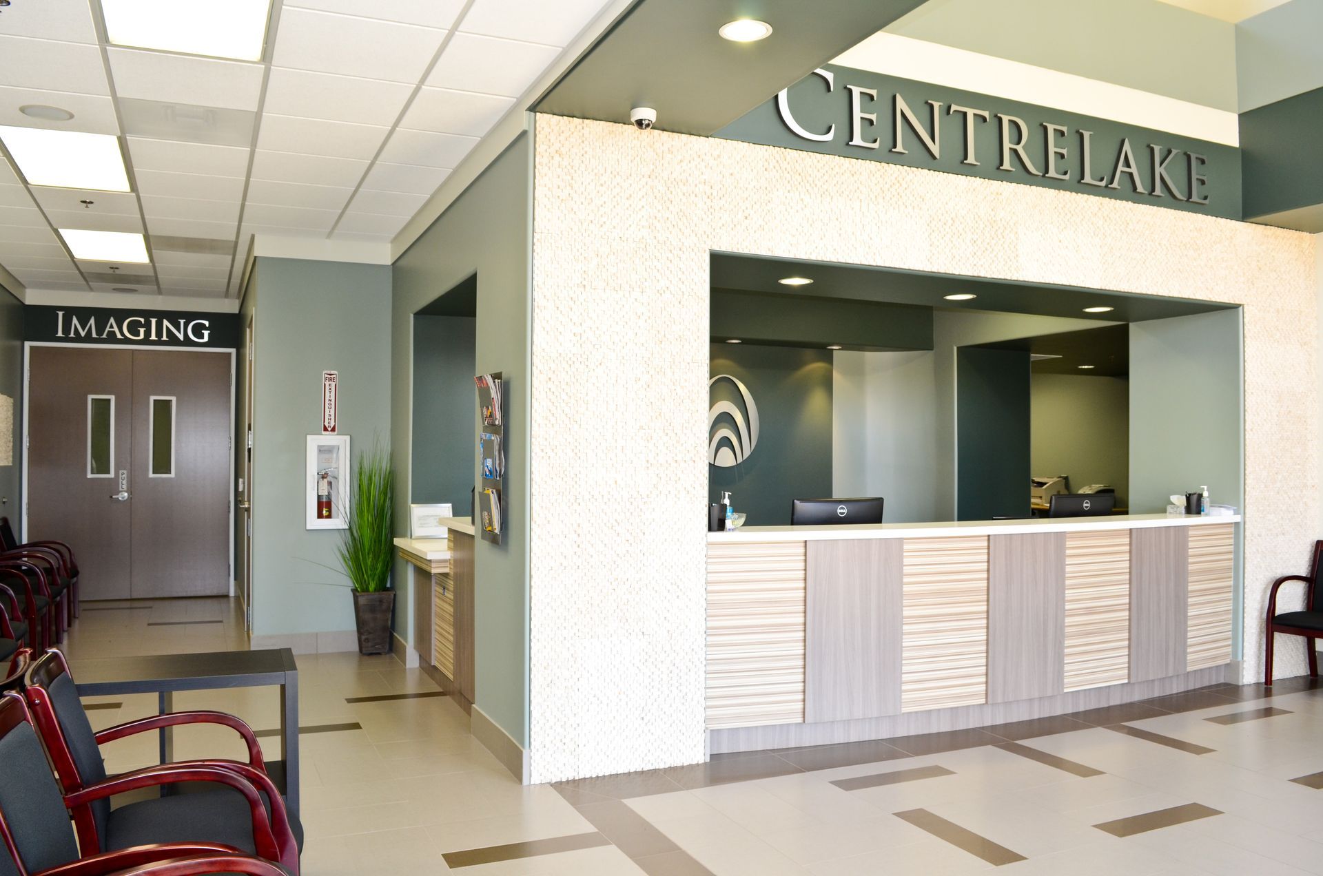Reception area in a medical office with a check-in desk and waiting chairs; the word 
