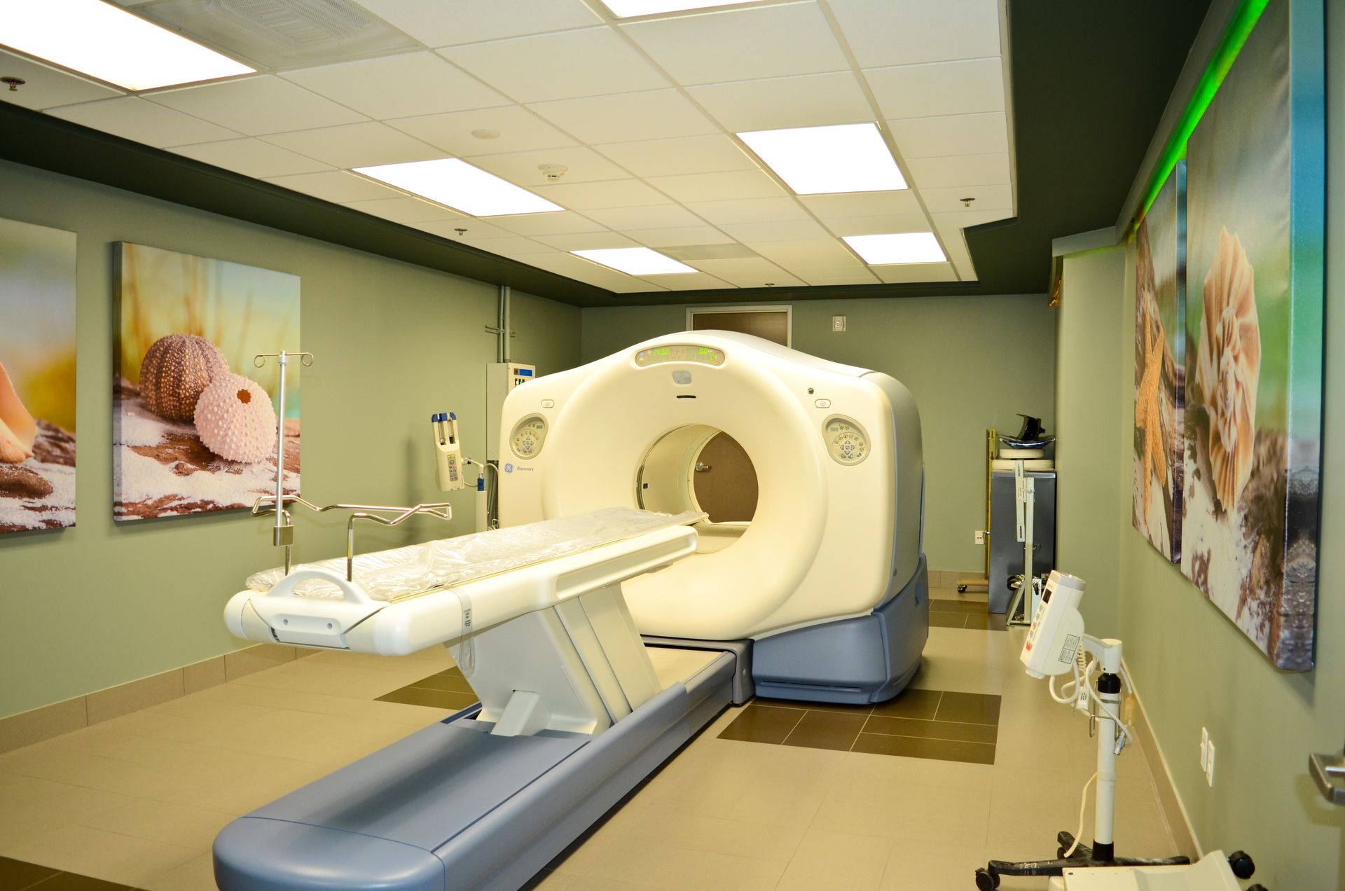 CT scan machine in a medical room with paintings on walls.